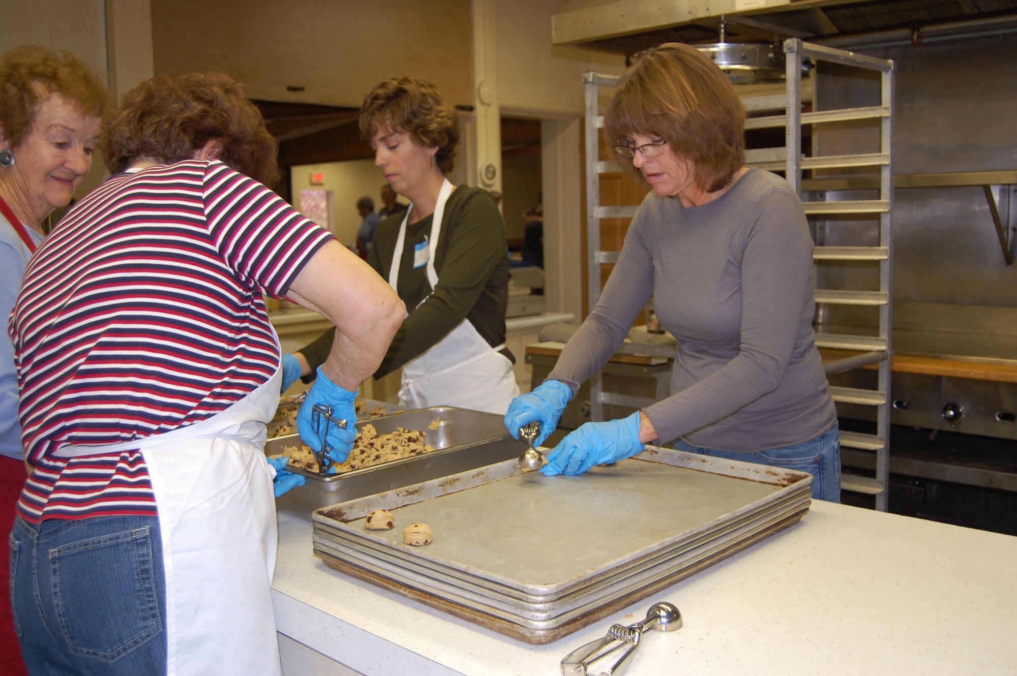 Volunteers for Operation Happy Holidays scoop chocolate chip cookie dough onto baking pans Dec. 1. (U.S. Air Force photo/Valerie Mullett)