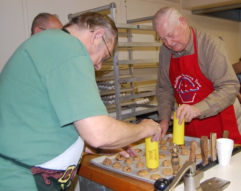 Jim Thul (left) and Jack Waterfield press down the chocolate chip cookie dough before it gets put into the oven for baking Dec. 1 as part of Operation Happy Holidays. (U.S. Air Force photo/Valerie Mullett)