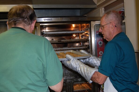 Al Maflin (right) and Jim Thul remove cookies from the oven at the VFW Dec. 1. These two volunteers have been assisting with Operation Happy Holidays since it started 10 years ago. (U.S. Air Force photo/Valerie Mullett)