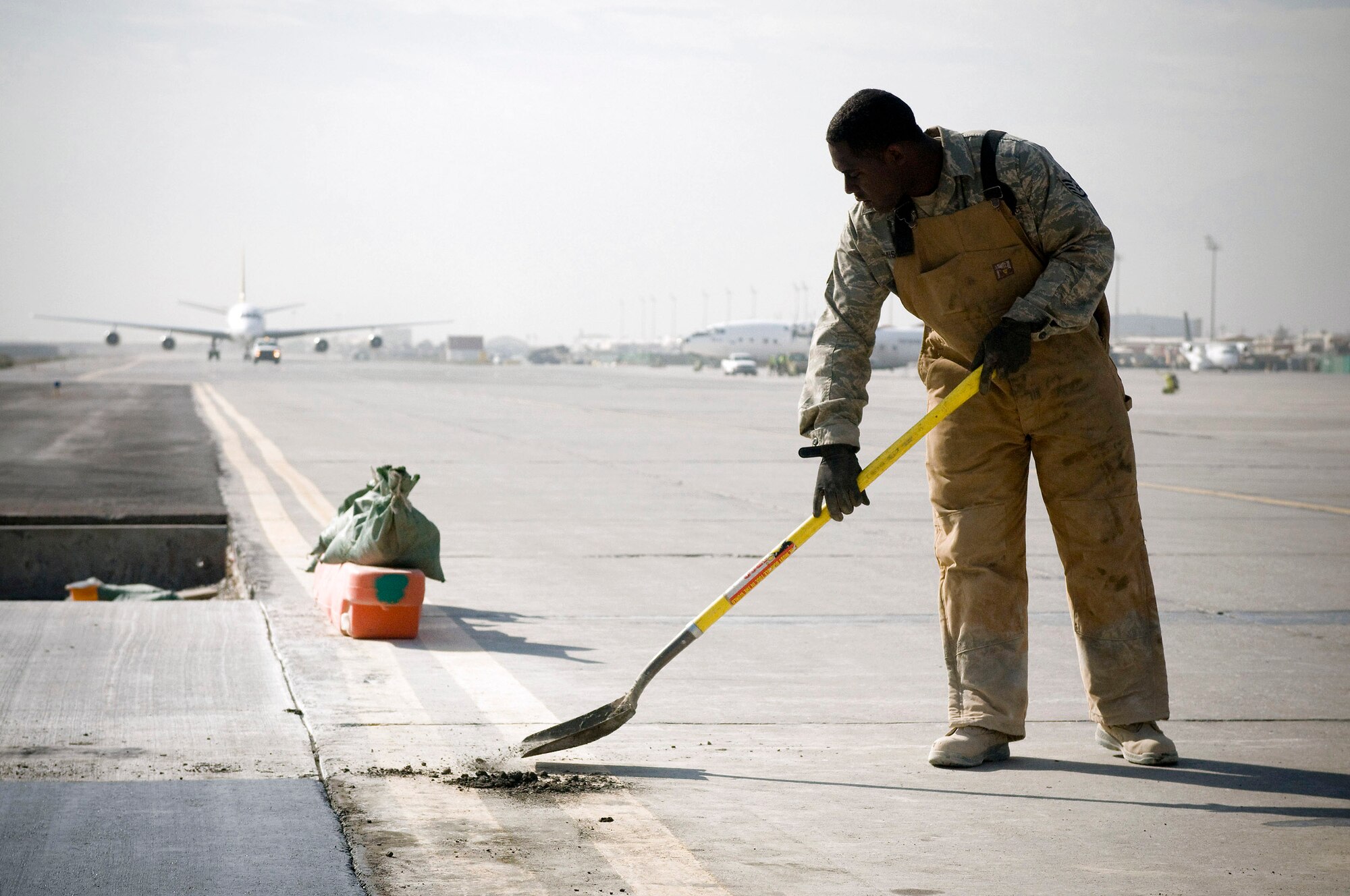 Staff Sgt. Shelton Jamison scoops away excess concrete on Thanksgiving Day at Bagram Airfield, Afghanistan. The Airmen of the 455th Expeditionary Civil Engineer Squadron must work quickly and efficiently to avoid causing traffic problems on the busy taxiway. Sergeant Jamison is assigned to the 455th ECES and deployed from Barksdale Air Force Base, La. (U.S. Air Force photo/Staff Sgt. Samuel Morse) 
