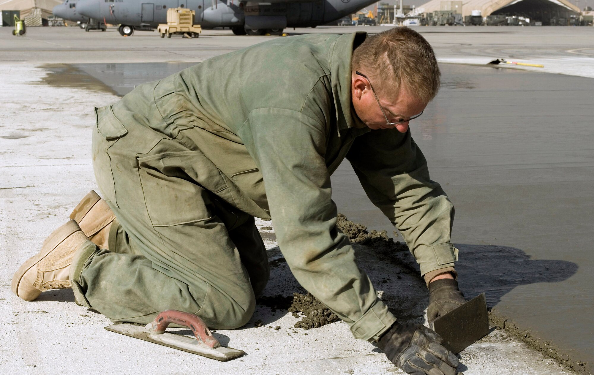 Staff Sgt. Edward Sells smoothes freshly poured concrete on the flightline Nov. 25 at Bagram Airfield, Afghanistan. More than 3,500 cubic meters of concrete are being poured to expand and construct ramps and taxiways as part of airfield expansion projects. Sergeant Sells is assigned to the a 455th Expeditionary Civil Engineer Squadron and deployed from Lackland Air Force Base, Texas. (U.S. Air Force photo/Staff Sgt. Rachel Martinez)