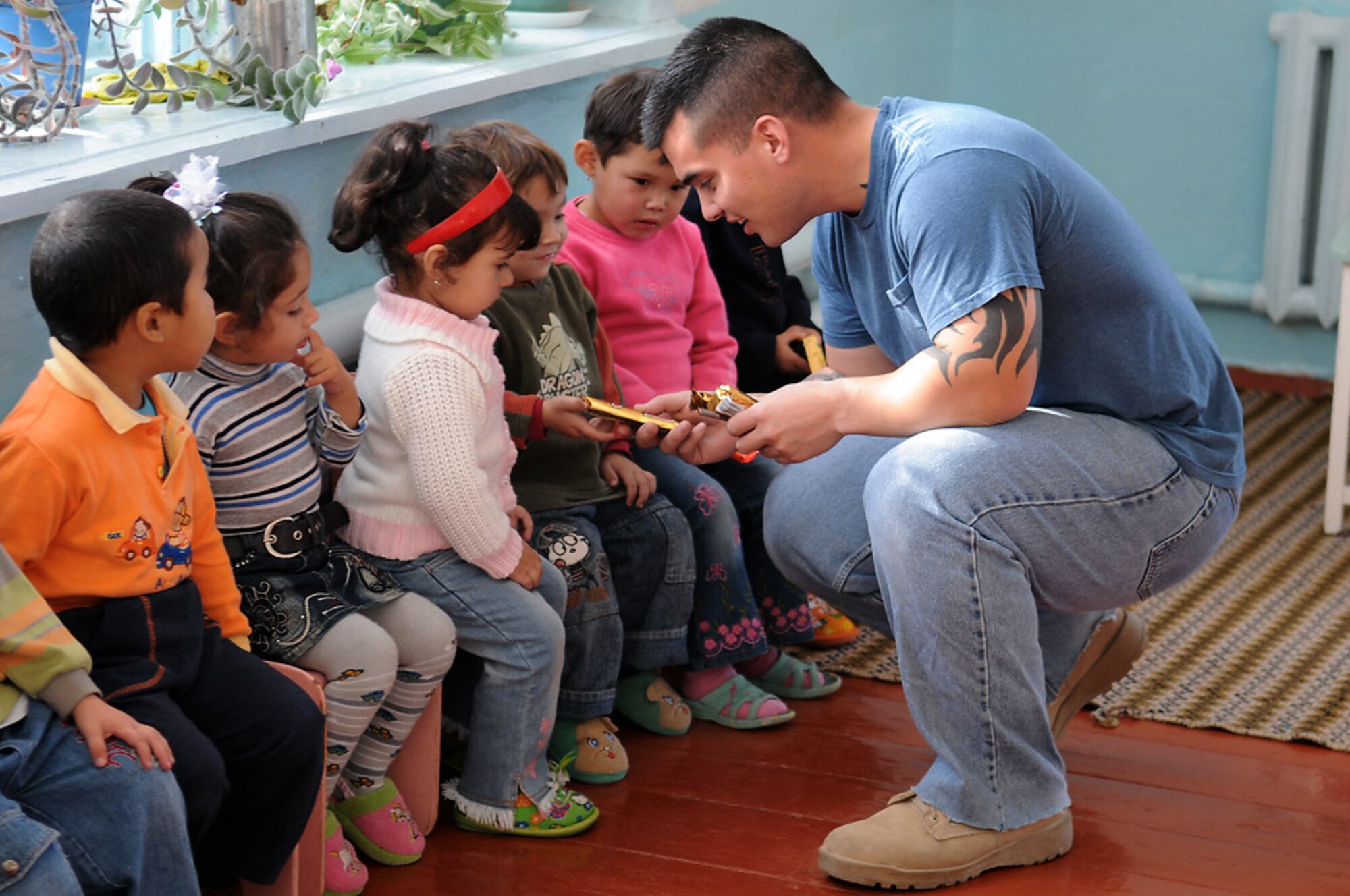 Staff Sgt. Brandon Arenibar hands out candy bars to the children at Vasilievika Elementary School Oct. 7 near Manas Air Base, Kyrgyzstan. Members of the 376th Air Expeditionary Wing Staff and Operations Group have supported the school since 2004, pulling together donations, pooling skills such as painting and carpentry and just spending time with the kids. Sergeant Arenibar is assigned to the 376th Expeditionary Operations Group. (U.S. Air Force photo/Senior Airman Ruth Holcomb) 
