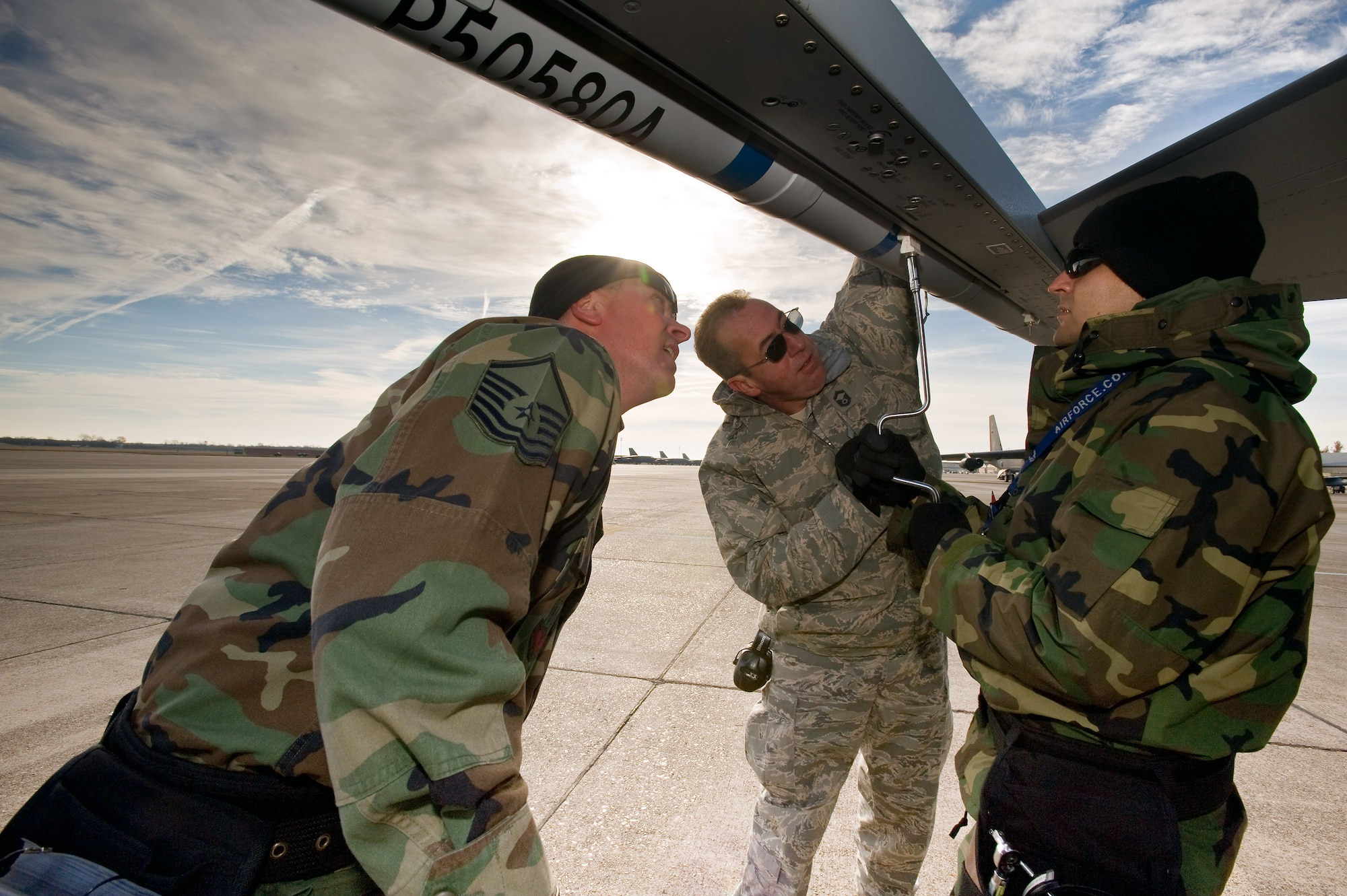 Staff Sgt. Richard Martinez tightens a mount that holds an air combat maneuvering instrumentation pod to the wing of an F-16 Fighting Falcon as Senior Master Sgt. Mark Jones and Master Sgt. Mark Caton observe and ensure it seats properly at Green Flag East at Barksdale Air Force Base, La. The Colorado Air National Guard members from Buckley AFB, Colo., are taking part in a predeployment exercise for Air Combat Command flying units. Sergeant Martinez is a 140th Aircraft Maintenance Squadron aircraft weapons specialist, Sergeant Jones is the 140th Maintenance Squadron weapons element NCO in charge, and Sergeant Caton is an aircraft armament specialist. (U.S. Air Force photo/Master Sgt. John Nimmo Sr.) 
