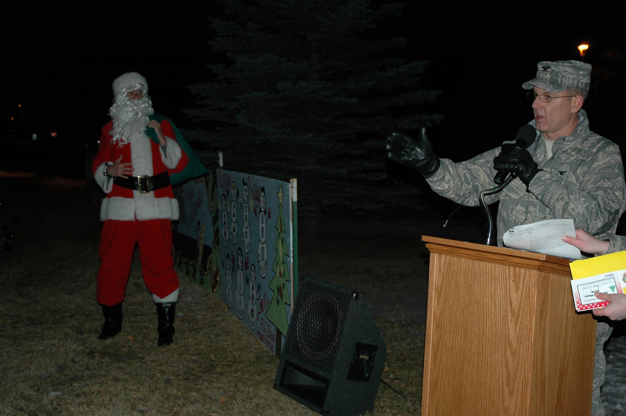 Col. Michael Fortney, 341st Missile Wing commander, and 'Santa Clause' prepare to announce the winners of this year's holiday card competition outside of the Grizzly Bend Club Dec. 5. The winners were: 3rd place, 341st Security Forces Squadron; 2nd place, 341st Security Forces Group; and 1st place went to the Health and Wellness Center. (U.S. Air Force photo/Senior Airman Emerald Ralston)