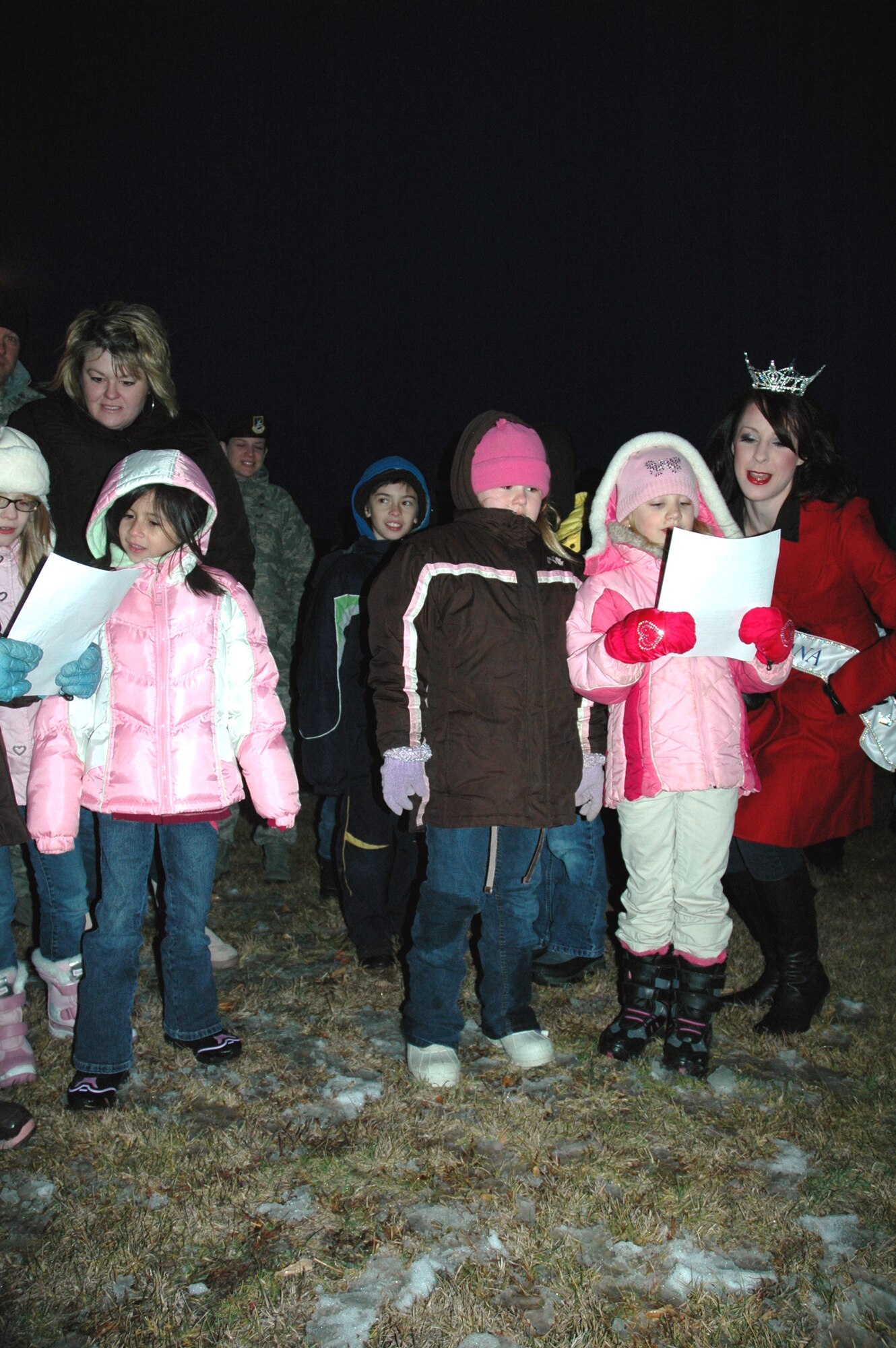 Miss Montana, Jennifer Hepner, right, sings holiday songs with a group of children outside the Grizzly Bend Club Dec. 5, prior to the base tree lighting ceremony. (U.S. Air Force photo/Senior Airman Emerald Ralston)