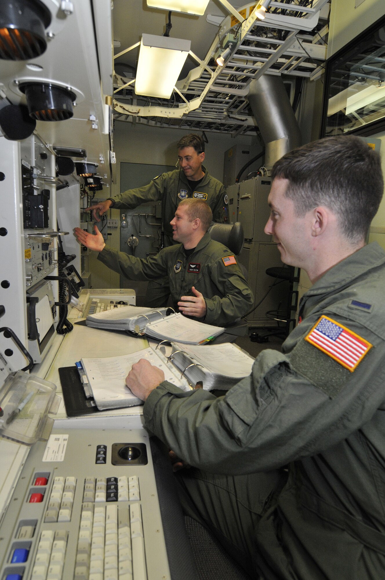 1st Lt. Mario Kuhn, 341st Operations Support Squadron deputy instructor, instructs 1st Lt. Donald Heaton, 12 Missile Squadron ICBM combat crew commander (left), and 1st Lt. Matthew Pecoraro, 341st OSS deputy instructor (right), in the Missile Procedures Trainer. They have just finished responding to an event and are discussing the principles involved. (U.S. Air Force photo/John Turner)