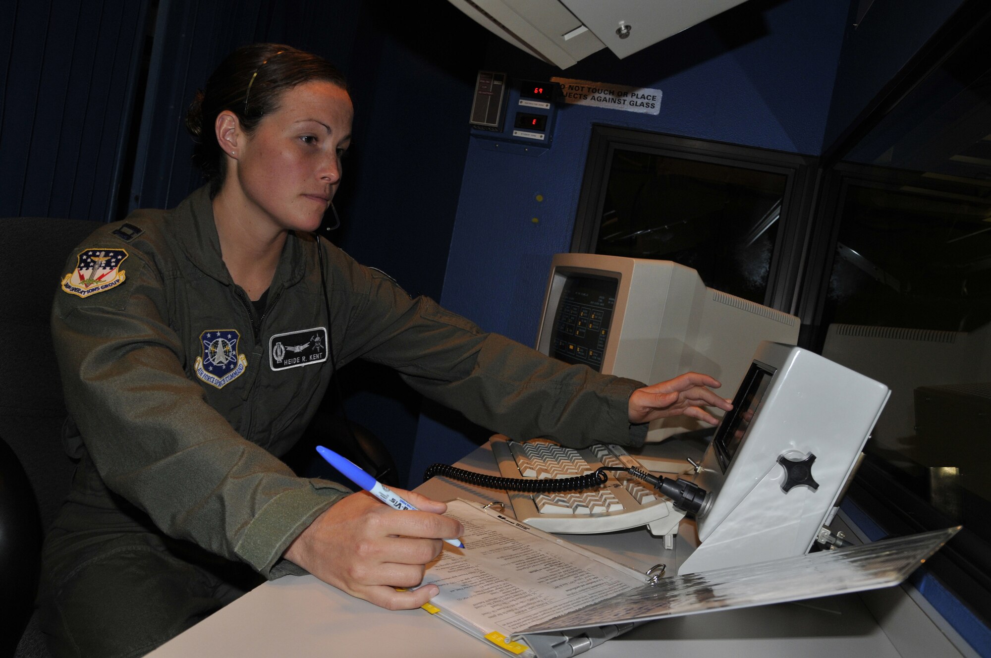 Capt. Heidi Kent, 341st Operations Group ICBM combat crew deputy evaluator, evaluates a crew in the Missile Procedures Trainer. She is advancing the trainer to events that the crew must respond to. She then monitors their reaction and rates them accordingly. The MPT simulates what missileers encounter in the field.  (U.S. Air Force photo/John Turner)
