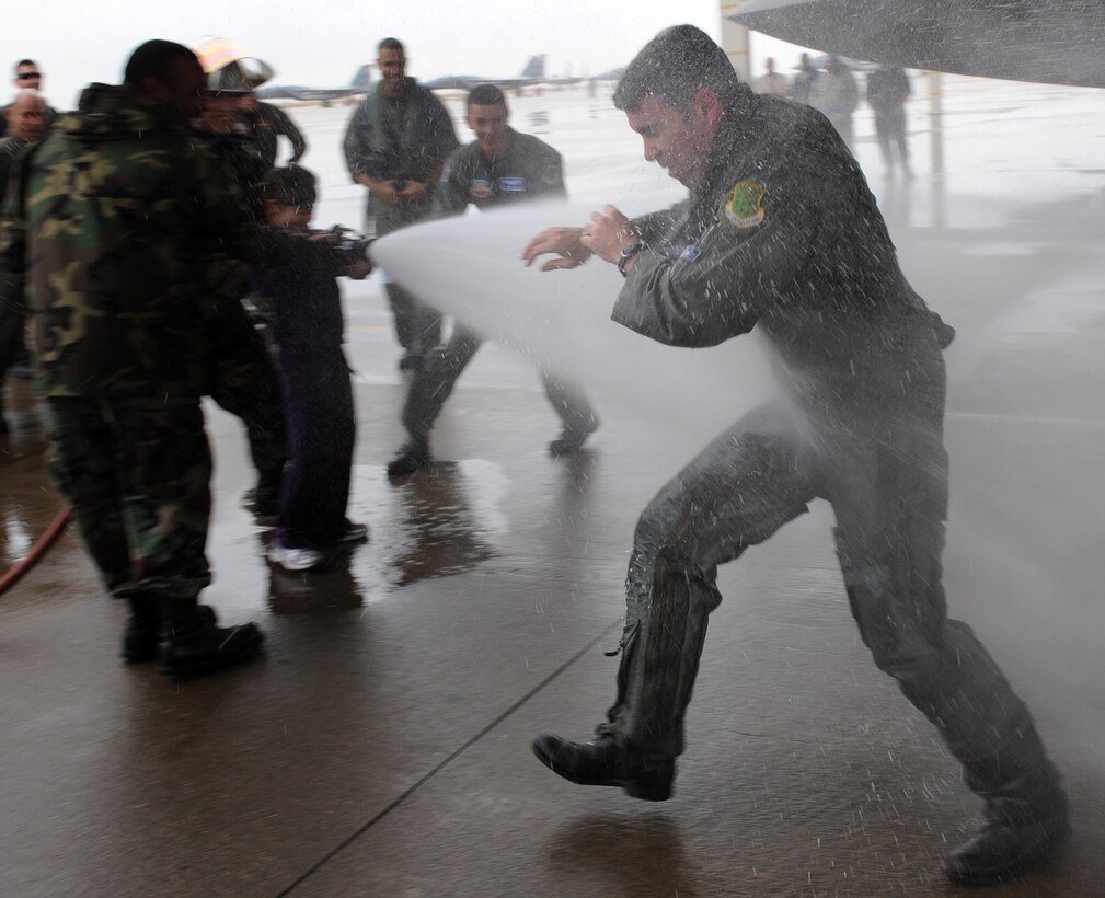 LANGLEY AIR FORCE BASE, Va. – Lt. Col. Kevin Fesler, 94th Fighter Squadron commander, tries to block the water as he is hosed down by his daughter after completing his fini flight Dec. 11. This flight was Colonel Fesler’s last flight on active duty before transitioning to the Air Force Reserve.  (U.S. Air Force photo/Airman 1st Class Zachary Wolf)