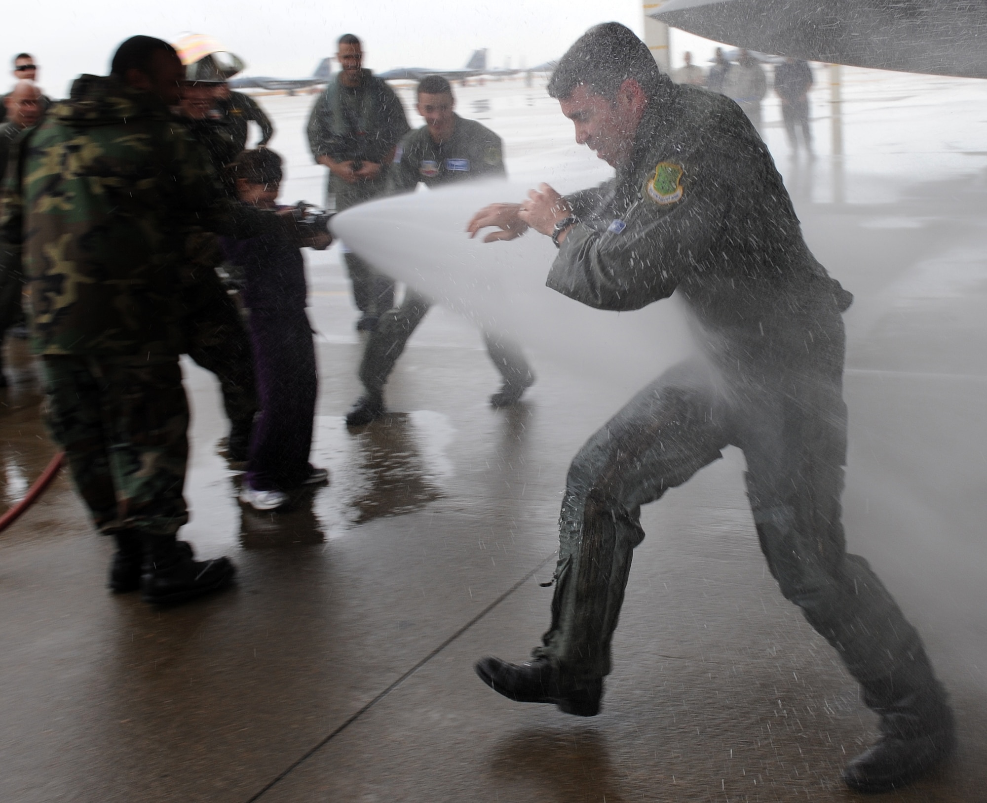 LANGLEY AIR FORCE BASE, Va. – Lt. Col. Kevin Fesler, 94th Fighter Squadron commander, tries to block the water as he is hosed down by his daughter after completing his fini flight Dec. 11. This flight was Colonel Fesler’s last flight on active duty before transitioning to the Air Force Reserve.  (U.S. Air Force photo/Airman 1st Class Zachary Wolf)