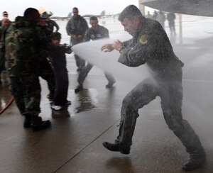 LANGLEY AIR FORCE BASE, Va. – Lt. Col. Kevin Fesler, 94th Fighter Squadron commander, tries to block the water as he is hosed down by his daughter after completing his fini flight Dec. 11. This flight was Colonel Fesler’s last flight on active duty before transitioning to the Air Force Reserve.  (U.S. Air Force photo/Airman 1st Class Zachary Wolf)