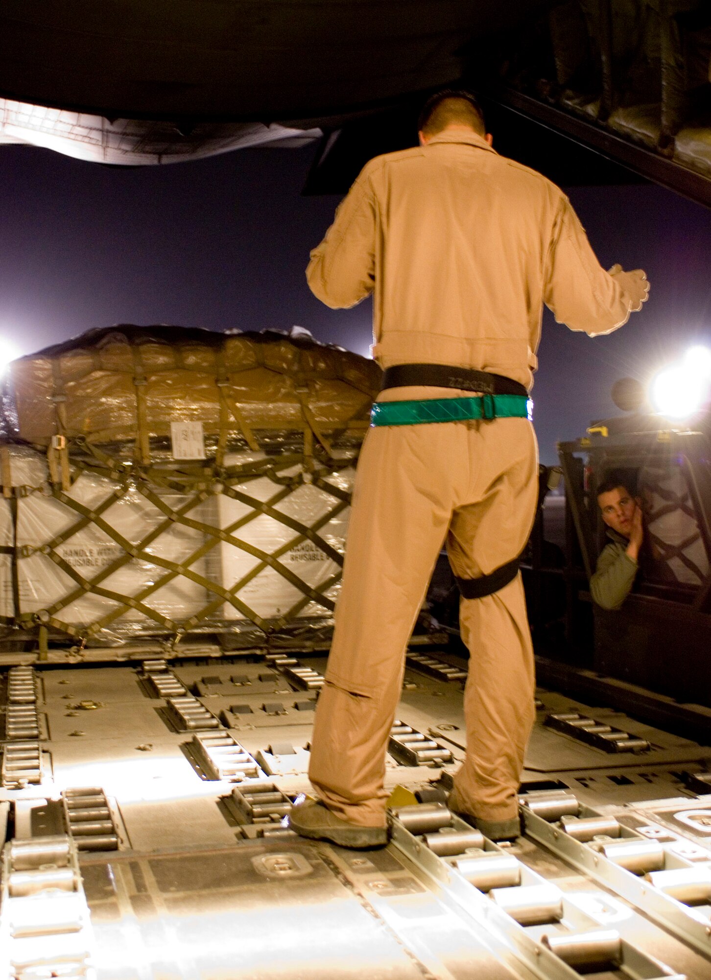 Staff Sgt. Shawn Engelsted, a loadmaster with the 774th Expeditionary Airlift Squadron, directs a k-loader driver while loading cargo onto a C-130H Hercules at Bagram Air Field, Afghanistan, Nov. 30. The cargo department of a C-130, originally designed to match the specifications of a railroad boxcar, can hold up to six cargo pallets. Sergeant Engelsted is deployed from the Minnesota Air National Guard. (U.S. Air Force photo by Staff Sgt. Rachel Martinez) (Released)