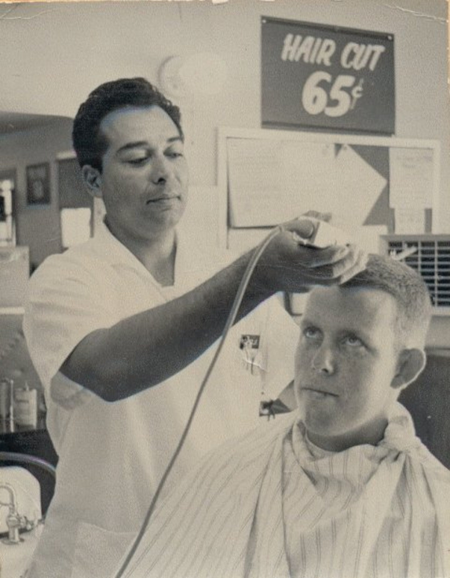 a vintage photo of an airman getting his hair shaved