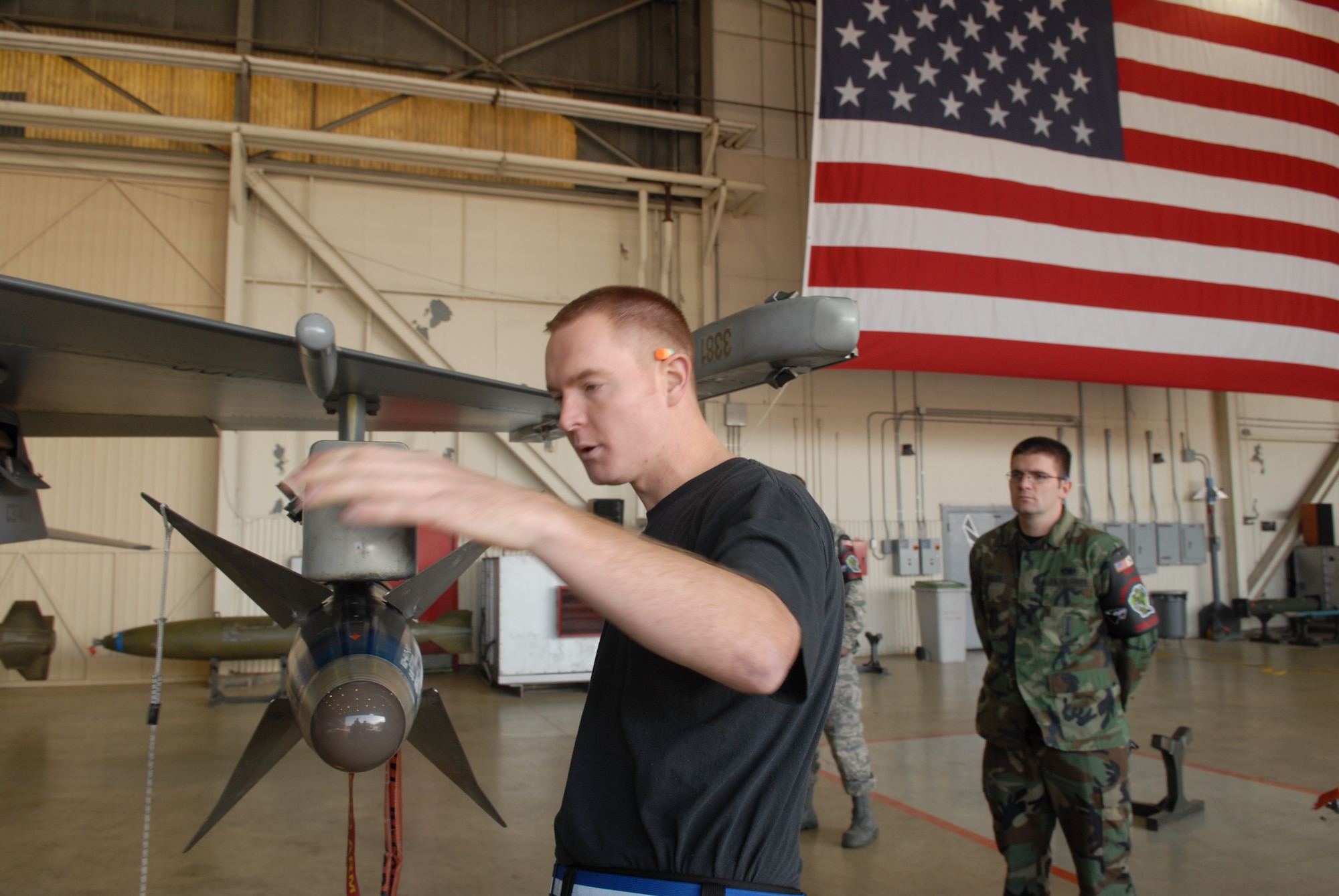 KUNSAN AIR BASE, Republic of Korea -- Staff Sgt. Jason Biddlecome, 8th Aircraft Maintenance Squadron, 35th Aircraft Maintenance Unit, loads  a weapon to an F-16 while an evaluator  watches during  the weapons load crew competition here Dec. 12. The best load crews from the  35th and 80th AMUs compete in the weapon load crew competition every month. US Air Force Photo By: Senior Airman Angela Ruiz)