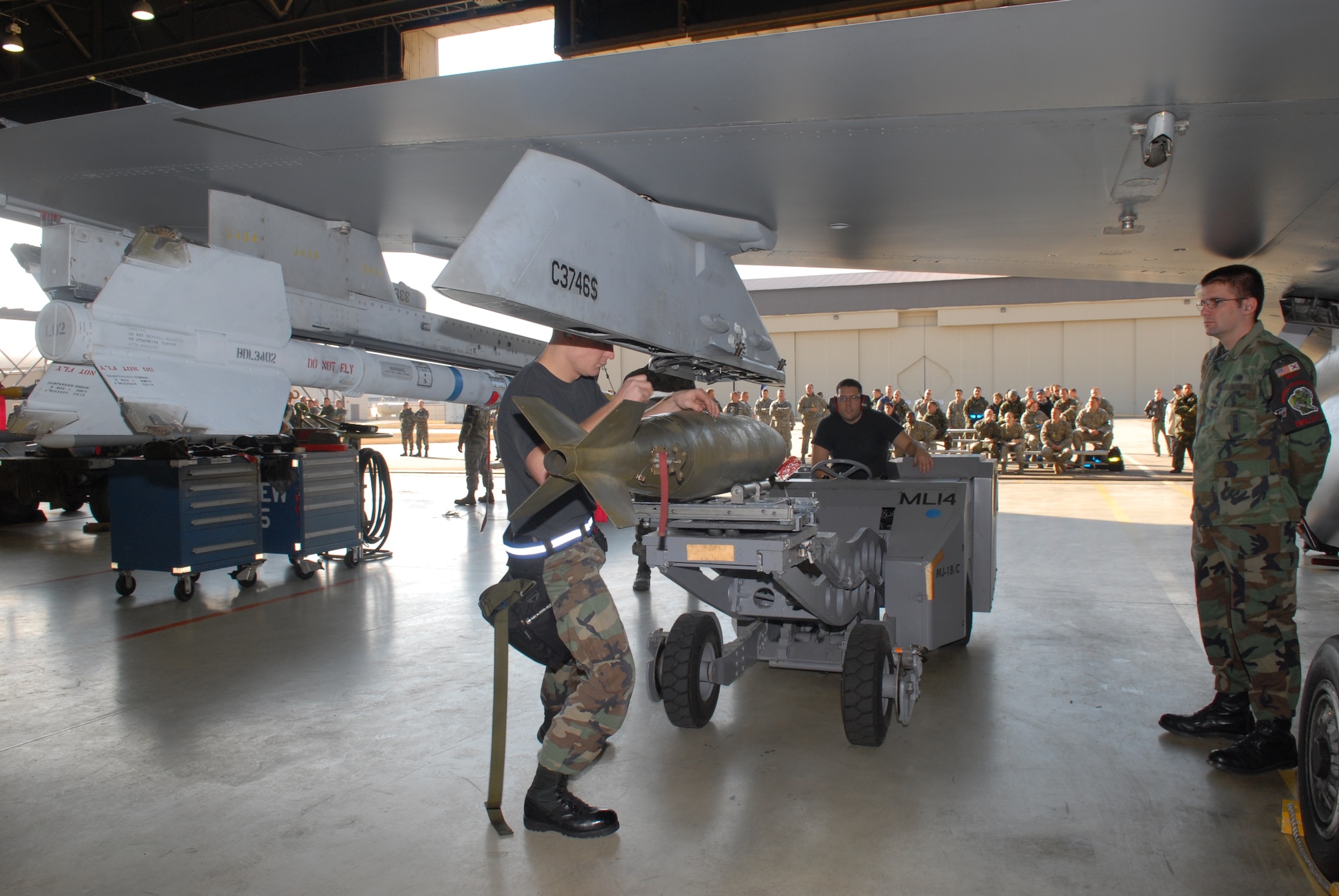 KUNSAN AIR BASE, Republic of Korea -- Staff Sgt. Jason Biddlecome and Senior Airman Gilbert Calberon, both from the 8th Aircraft Maintenance Squadron, 35th Aircraft Maintenance Unit  load a  weapon on an F-16 while spectators and evaluators watch during a weapons load crew competition here Dec. 12.  The best load crews from the  35th and 80th AMUs compete in the weapon load crew competition every month. US Air Force Photo By: Senior Airman Angela Ruiz)