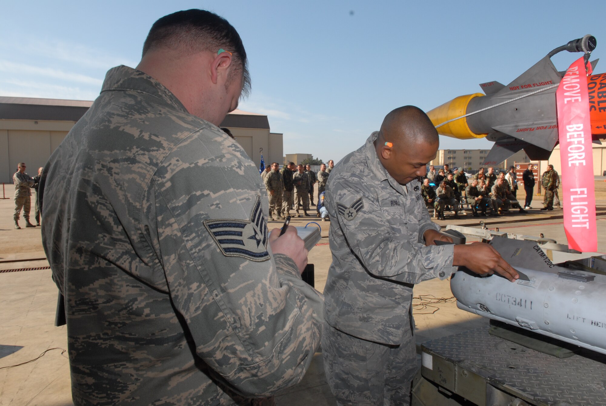 KUNSAN AIR BASE, Republic of Korea -- Staff Sgt. Erick Michael checks a technical order while Senior Airman Demetrick  Russell, both of the  8th Aircraft Maintenance Squadron, 80th Aircraft Maintenance Unit, participates in a weapons load crew competition here Dec. 12.  The best load crews from the  35th and 80th AMUs compete in the weapon load crew competition every month. US Air Force Photo By: Senior Airman Angela Ruiz)