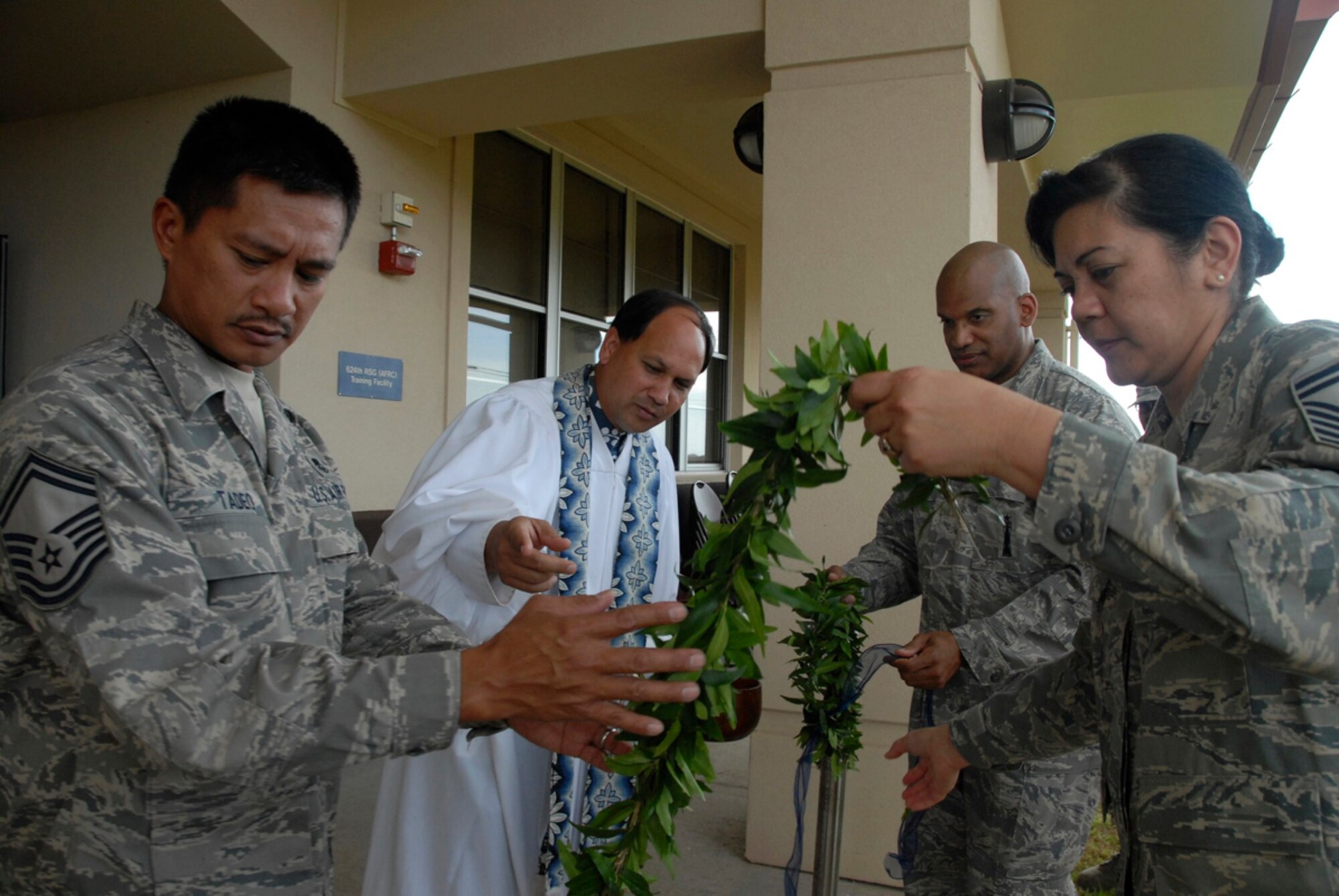 Kahu Kordell Kedoa, a pastor from Kamehameha Schools in Honolulu, directs Senior Master Sgts. Ricarte Tadeo, Corina Seitz and Bob Prather, 624th Regional Support Group, to untie a maile lei as part of a Hawaiian blessing ceremony commemorating the opening of a new building for the 624th Regional Support Group December 7, 2008 at Hickam Air Force Base, Hawaii.  The building represents the first structure build specifically for the 624th RSG on the base.  (U.S. Air Force photo by Staff Sgt. Jennie Chamberlin

