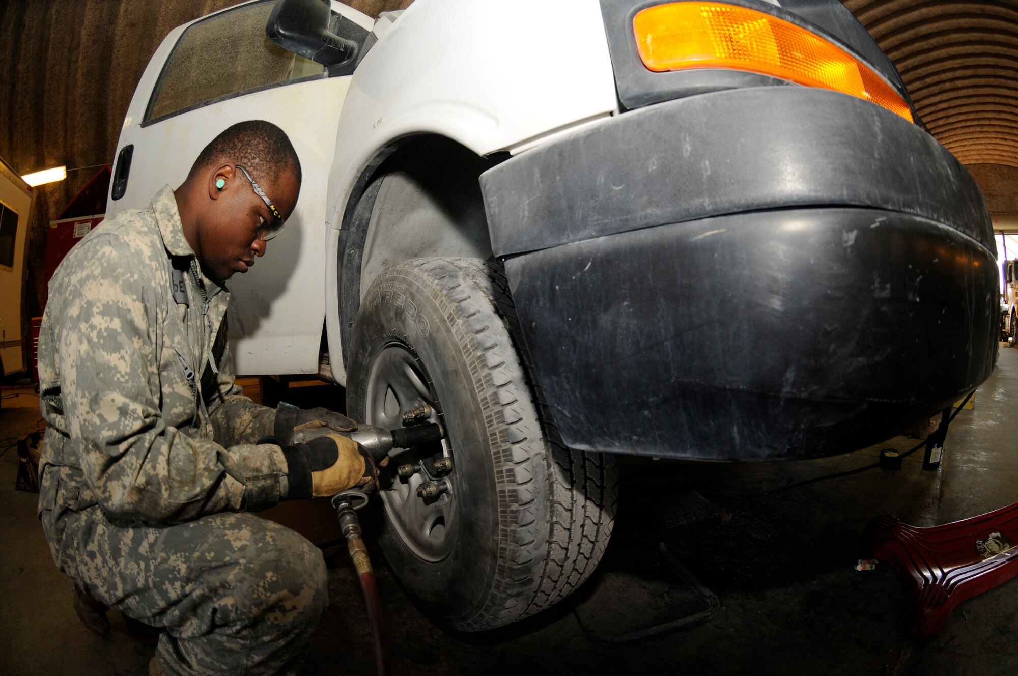 Senior Airman Marcus Reese, vehicle maintenance journeyman assigned to the 379th Expeditionary Logistics Readiness Squadron, removes lug nuts using an air impact gun to change a tire Dec. 11, at an undisclosed air base in Southwest Asia.  Airman Reese, a native of Cleveland, Ohio, is deployed from Port Clinton National Guard Base, Ohio, in support of Operations Iraqi and Enduring Freedom and Joint Task Force-Horn of Africa. (U.S. Air Force photo by Staff Sgt. Darnell T. Cannady/Released)