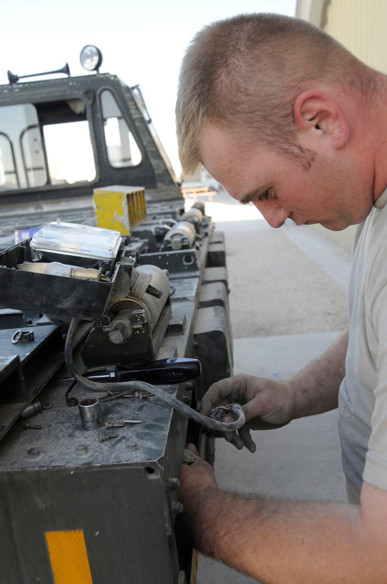 Senior Airman Michael Poole, vehicle maintenance journeyman assigned to the 379th Expeditionary Logistics Readiness Squadron, repairs a headlight assembly on a 60K loader Dec. 11, at an undisclosed air base in Southwest Asia.  Airman Poole, a native of Little Rock, Ark., is deployed from Elmendorf Air Force Base, Alaska, in support of Operations Iraqi and Enduring Freedom and Joint Task Force-Horn of Africa. (U.S. Air Force photo by Staff Sgt. Darnell T. Cannady/Released)