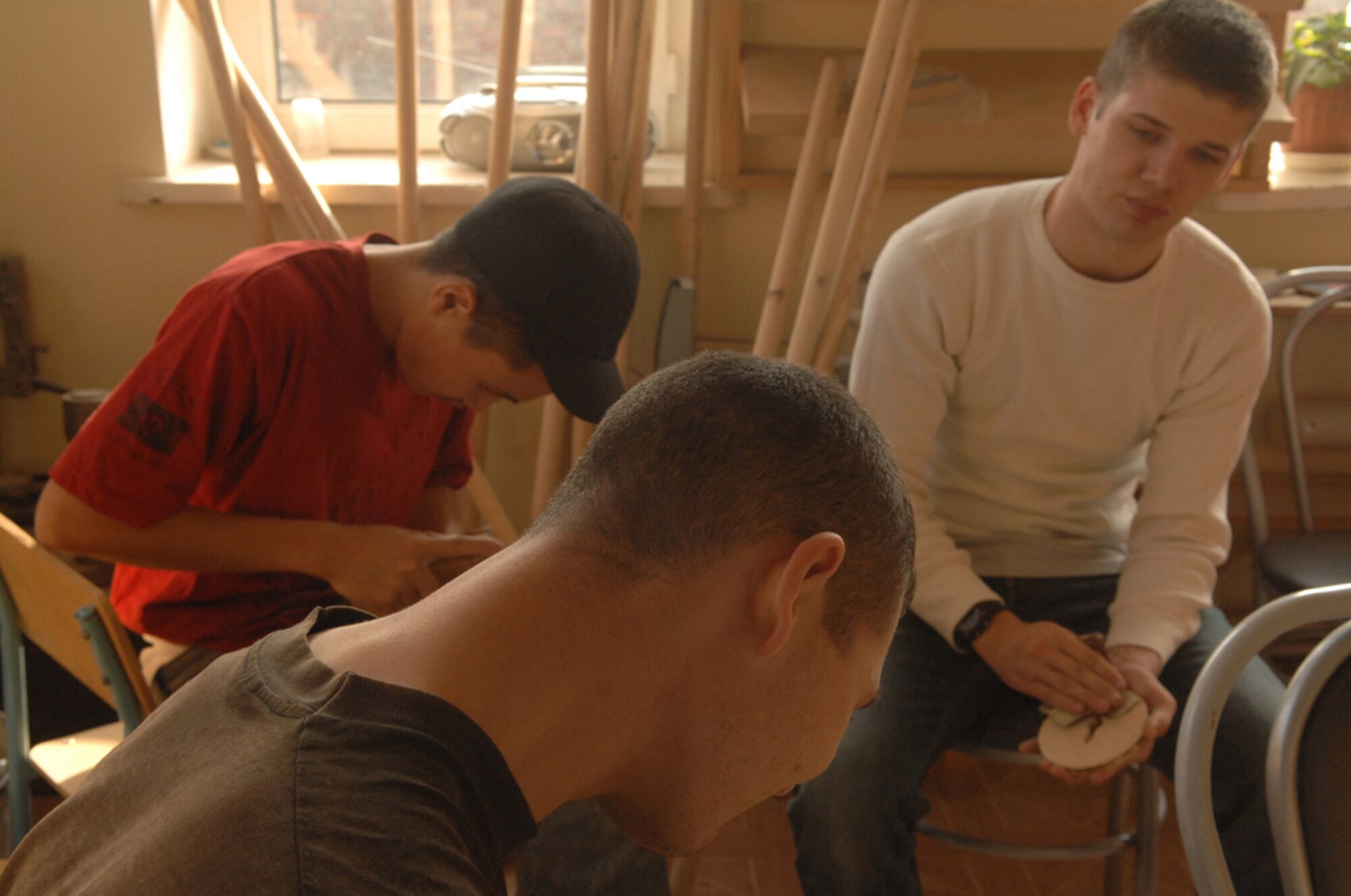 MANAS AIR BASE, KYRGYZSTAN - Senior Airman Alexander Farver, 376th Air Expeditionary Wing, helps Uventus Teenage Training Center students sand blocks during a wood shop class, Dec.8. Deployed servicemembers from Manas have supported the training center through weekly visits and donations such as school supplies. The center was started through the efforts of a retired Army 1st Sergeant Jim Carney who made numerous deployments to Kyrgyzstan before retiring. (Air Force photo / Tech. Sgt. Michael Voss)