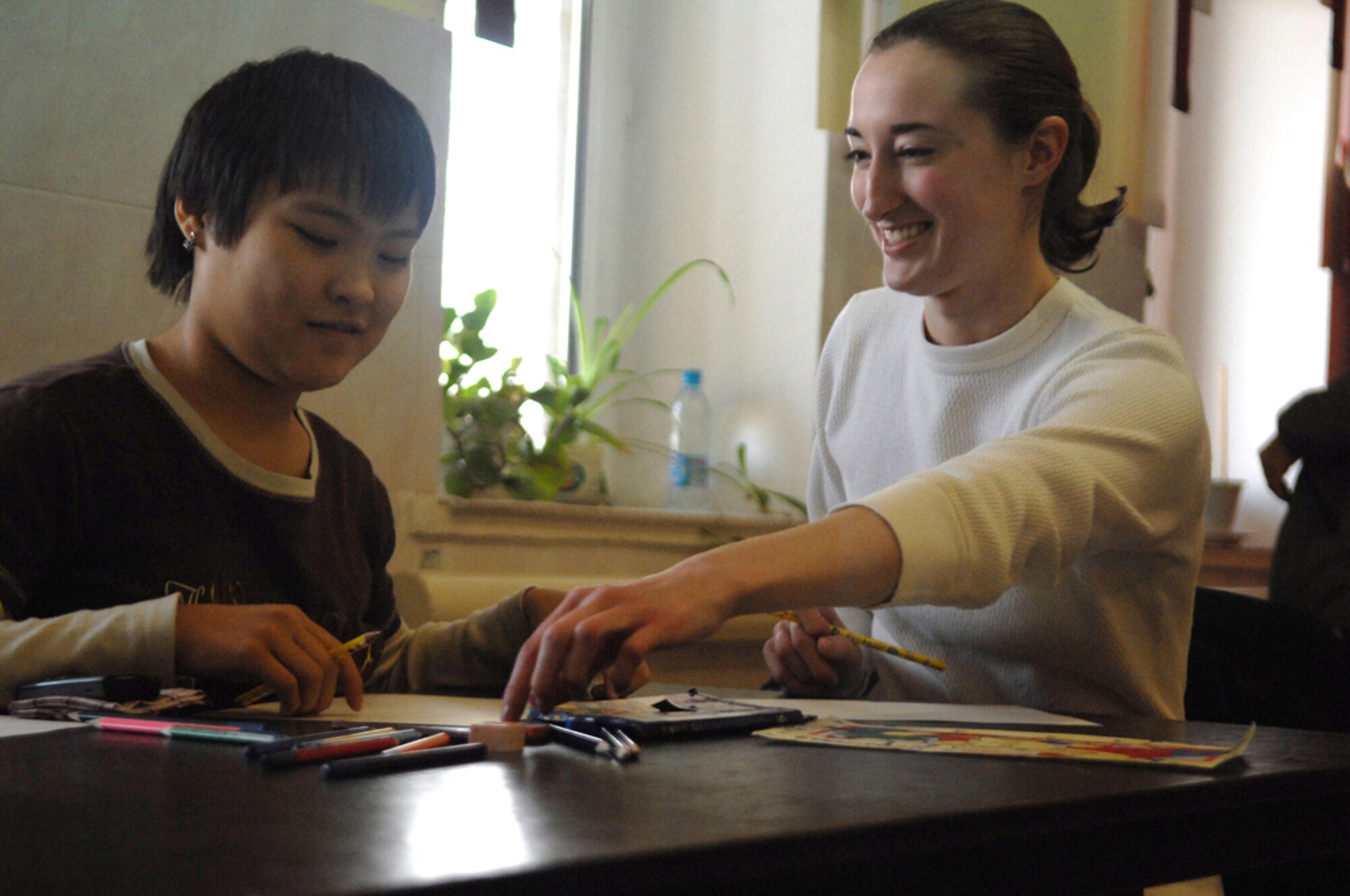 MANAS AIR BASE, KYRGYZSTAN - Airman 1st Class Victoria Cornish, 376th Expeditionary Logistics Readiness Squadron technician, helps a Kyrgyz girl color a picture during a trip to the Uventus Teenage Training Center. Deployed servicemembers from Manas have supported the training center through weekly visits and donations such as school supplies. The center was started through the efforts of a retired Army 1st Sergeant Jim Carney who made numerous deployments to Kyrgyzstan before retiring. (Air Force photo / Tech. Sgt. Michael Voss)
