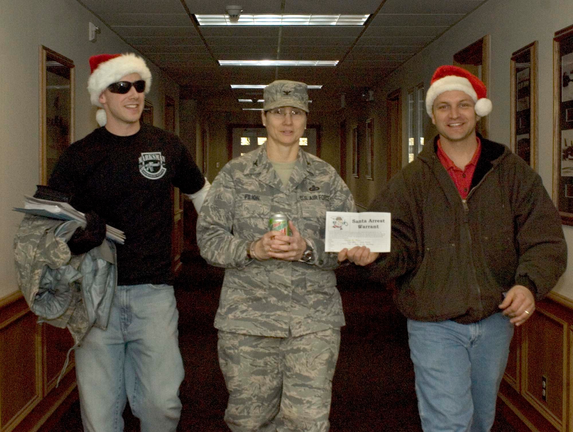FAIRCHILD AIR FORCE BASE, Wash. – Col. Suzanne Filion, 92nd Mission Support Group commander, is arrested for the Santa Lock-up by Tech Sgt. Max Talley and Senior Airman Mark Green, 92nd Security Forces Squadron, Dec. 4. Money raised from the Santa Lock-up supports organizations such as Drug Abuse Resistance Education, a police officer-led series of classroom lessons taught from Kindergarten through the 12th grade. (U.S. Air Force photo / Airman 1st Class Darlene West)

