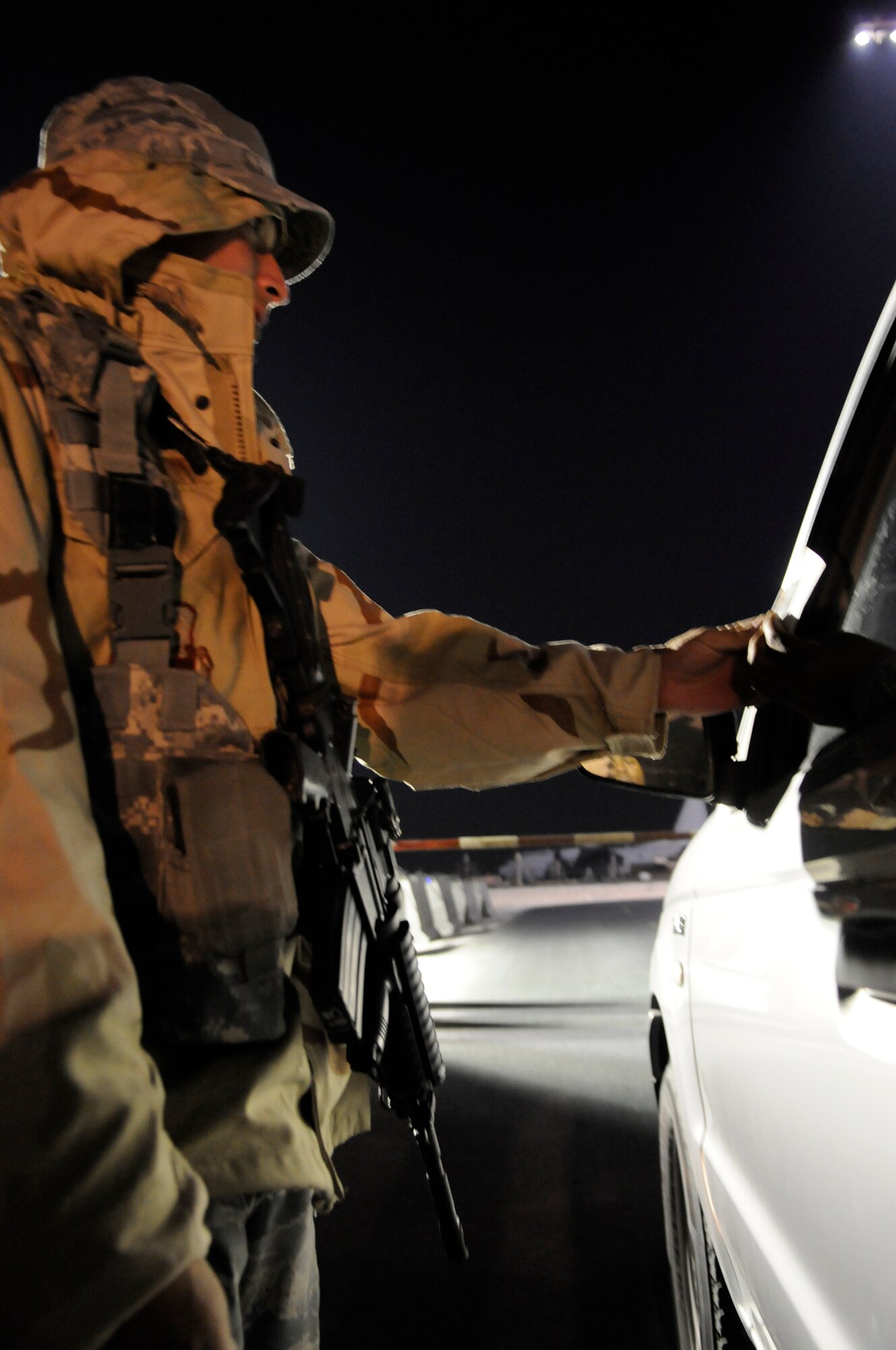 Airman 1st Class Raymond Taboada, a security forces journeyman assigned as entry control point sentry for the 379th Expeditionary Security Forces Squadron, checks an ID card and airfield driving permit prior to allowing a vehicle through a checkpoint, Dec. 12, at an undisclosed air base in Southwest Asia.  Airman Taboada, a native of Port Charlotte, Fla., is deployed from Tyndall Air Force Base, Fla., in support of Operations Iraqi and Enduring Freedom and Joint Task Force-Horn of Africa.  (U.S. Air Force photo by Tech. Sgt. Michael Boquette/Released)