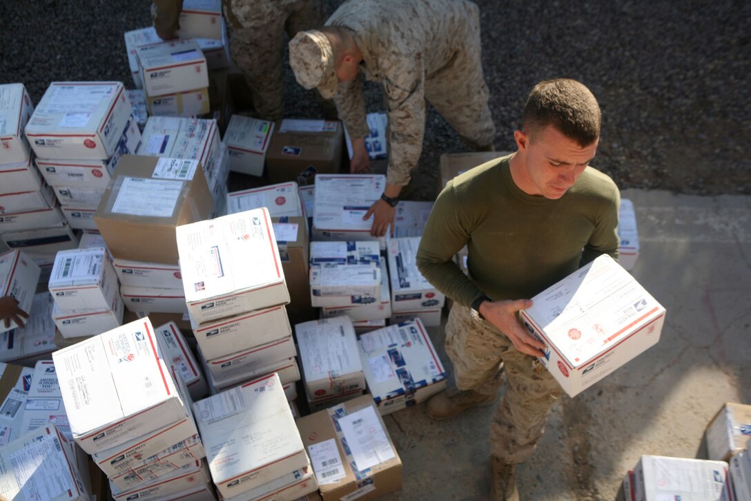 Lance Cpl. Nathaniel Z. Udovich, a 21-year-old mail clerk from Trenton, Mo., with Headquarters Company, 1st Battalion, 4th Marine Regiment, Regimental Combat Team 1, sorts packages for Marines during the holiday season at Camp Baharia in Fallujah, Iraq.