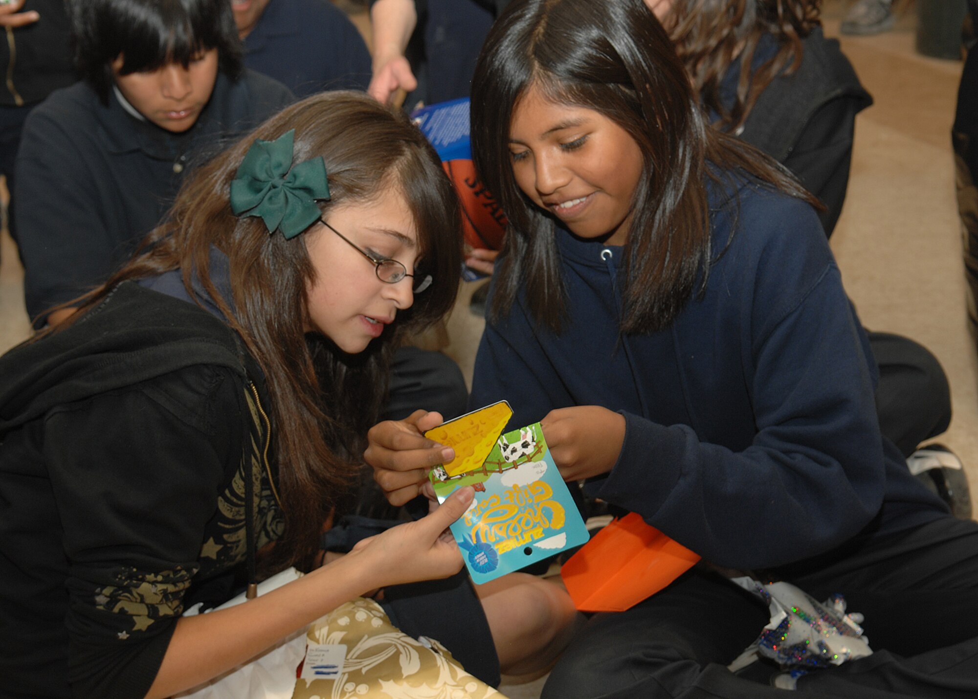 Students from St. Xavier Mission School show each other the Christmas toys they received from Santa and Mrs. Claus Dec. 15. Mr. and Mrs. Claus were at the school to host the Santas in Blue event in which Airmen from D-M come together to give gifts to children for Christmas. The St. Xavier Mission School goes from kindergarten to eighth grade.  (U.S. Air Force Photo/Senior Airman Jacqueline Romero) 