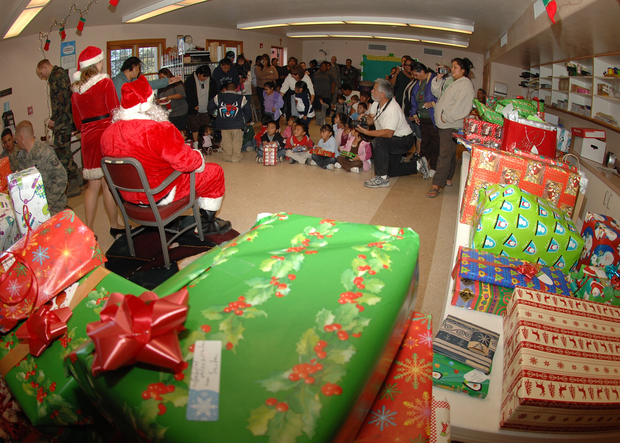 Santa and Mrs. Claus hand out presents to students from St. Xavier Mission School Dec. 15.  Mr. and Mrs. Claus were at the school to host the Santas in Blue event which Airmen from D-M come together to give gifts to children for Christmas. The St. Xavier Mission School goes from kindergarten to eighth grade.  (U.S. Air Force Photo/Senior Airman Jacqueline Romero)  
