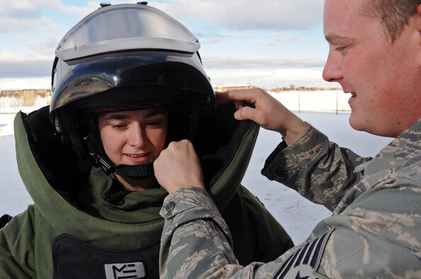 Tech. Sgt. David Fitzpatrick, 28th Civil Engineer Squadron Explosive Ordinance Disposal operator, assists Senior Airman Alicia Goodner, 28th CES EOD operator, don a bomb suit protective helmet here, Dec. 11. The Air Force EOD mission is to protect people, facilities, and resources from the damaging effects of unexploded ordnance, hazardous components, and devices. (US Air Force photo/Airman 1st Class Corey Hook)