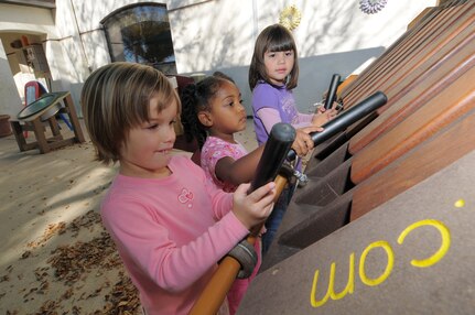 Libertie Barnett, far left, and Meya Martin, center, join Micah Prada in making music, Nov. 12, with some of the oversized instruments at a Child Development Center on Randolph Air Force Base. (U.S. Air Force photo by Melissa Peterson)
