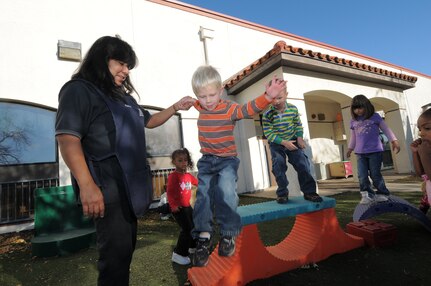 Child Development Center staff member Kathy Mora, left, helps Weston Outlaw down from a high spot during outdoor time Nov. 12 at the facility. (U.S. Air Force photo by Melissa Peterson)