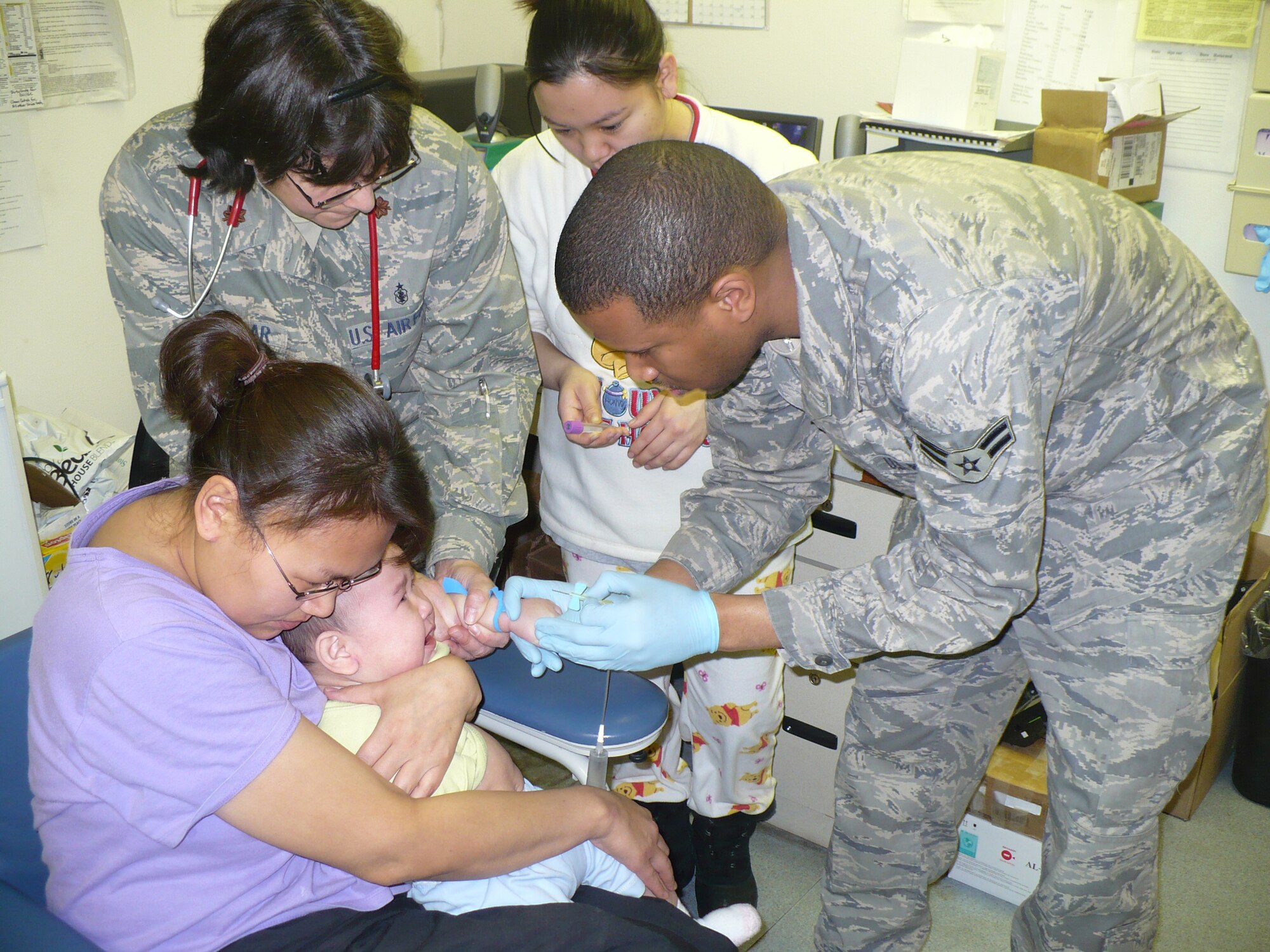 SELAWIK, Alaska -- Maj. Kerin McKellar and Airman 1st Class Nathaniel Jackson, 3rd Medical Operations Squadron, give an infant a shot during the Taakti Topcover mission. Members of the 3rd Medical Group assisted natives in rural Alaska. The Arctic Medics assisted nearly 800 patients and more than $115,000 worth of medical care. (U.S. Air Force photo)