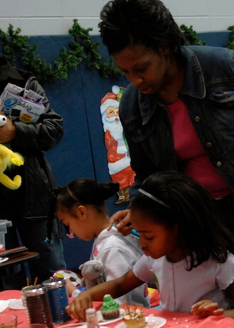 Anita Williams helps daughter Kanisha Porter decorate cupcakes at the annual holiday party  on Charleston AFB Dec. 13.  Youth Programs hosts the annual holiday party where base youth have the opportunity to meet Santa Claus, get their faces painted along with various other activities.Kanisha is the daughter of Ms. Williams and Tech. Sgt. Eugene Porter with the 437th Aerial Port Squadron. (U.S. Air Force photo/Airman 1st Class Katie Gieratz)