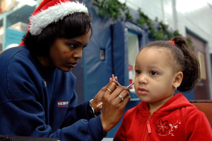 Gina Burdett paints Aaron Anderson's face at the holiday party on Charleston AFB Dec. 13. Youth Programs hosts the annual holiday party where base youths have the opportunity to meet Santa Claus along with various other activities. Aaron is the daughter of Doug and Sharon Defreitas who is assigned to the 437th Force Support Squadron. Ms. Burdett is with the 437th Force Support Squadron. (U.S. Air Force photo/Airman 1st Class Katie Gieratz)