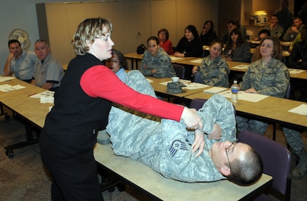 Kim Houk, Health and Wellness Center exercise physiologist, demonstrates proper crunch techniques with the help of Staff Sgt. Larry Fortner, 12th Mission Support Squadron, during a Wingman Day seminar Dec. 12. Airmen and civilians spent the day participating in briefings, training and entertainment activities to foster teamwork and promote esprit de corps. (U.S. Air Force photo by Don Lindsey)