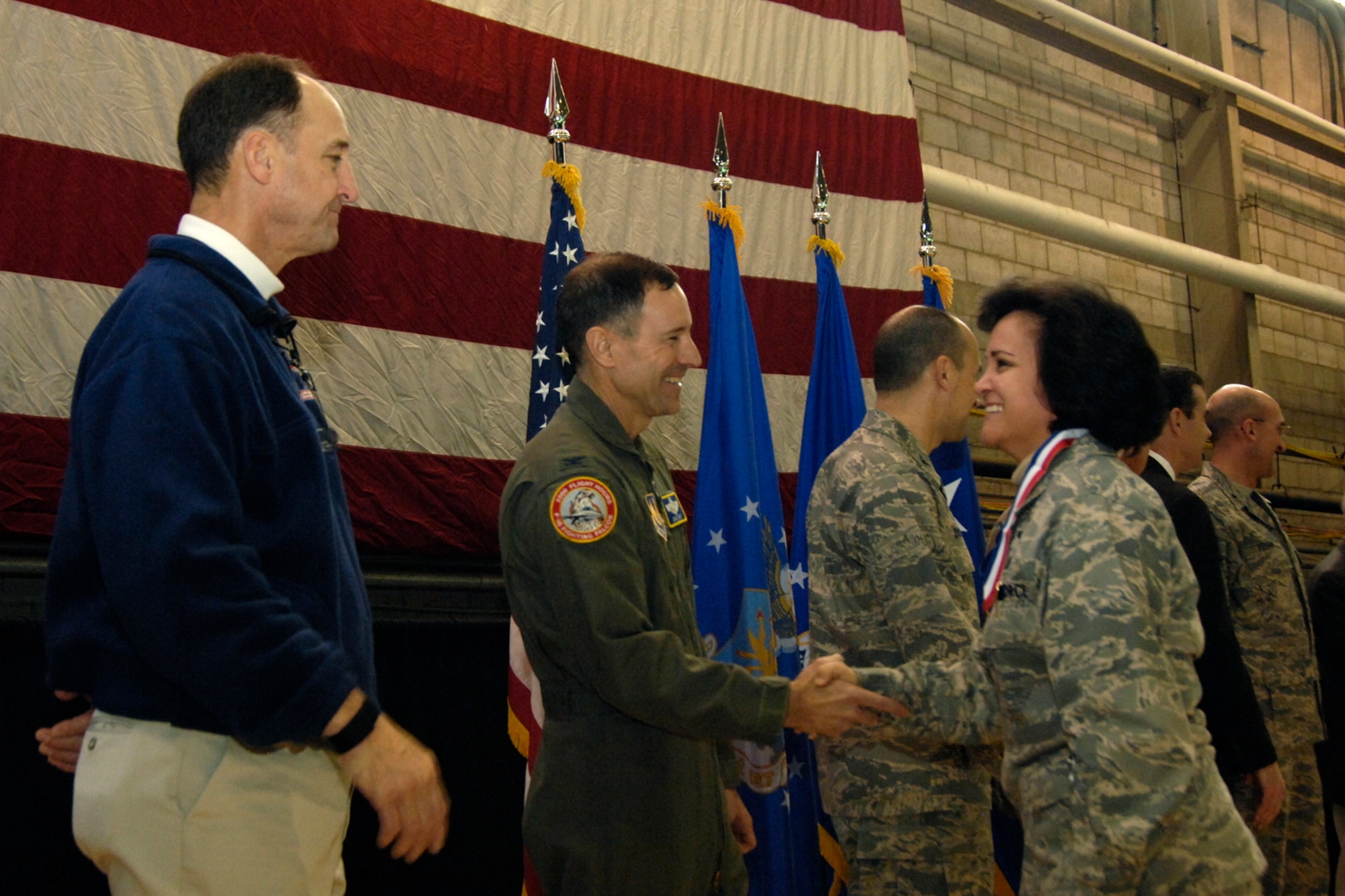 HANSCOM AIR FORCE BASE, Mass. – Maj. Elisa Valenzuela (right) is welcomed home by Col. David Orr (second from left), 66th Air Base Wing commander and former New England Patriots quarterback Steve Grogan (left) during the Heroes’ Homecoming celebration that took place Dec. 12. The event welcomed home more than 45 Hanscom Airmen who have served on deployments during the past six months. (U.S. Air Force photo by Linda LaBonte Britt)