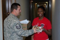 MINOT AIR FORCE BASE, ND – Airman 1st Class Charphanik Conway, 5th Force Support Squadron food services apprentice, receives a package of cookies and other treats from Master Sgt. Lowell Cormier, acting 5th Force Support Squadron first sergeant, as part of the annual base cookie drive. The drive is a way to bring season’s greetings to the Airmen living in the dormitories who can’t be home for the holidays. (Official U.S. Air Force photo by SSgt Keith Ballard)