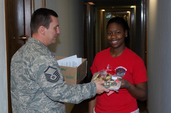 MINOT AIR FORCE BASE, N.D. -- Airman 1st Class Charphanik Conway, 5th Force Support Squadron food services apprentice, receives a package of cookies and other treats from Master Sgt. Lowell Cormier, 5th Force Support Squadron acting first sergeant, as part of the annual base cookie drive. The drive is a way to bring season’s greetings to the Airmen living in the dormitories who can’t be home for the holidays. (U.S. Air Force photo by Staff Sgt. Keith Ballard)