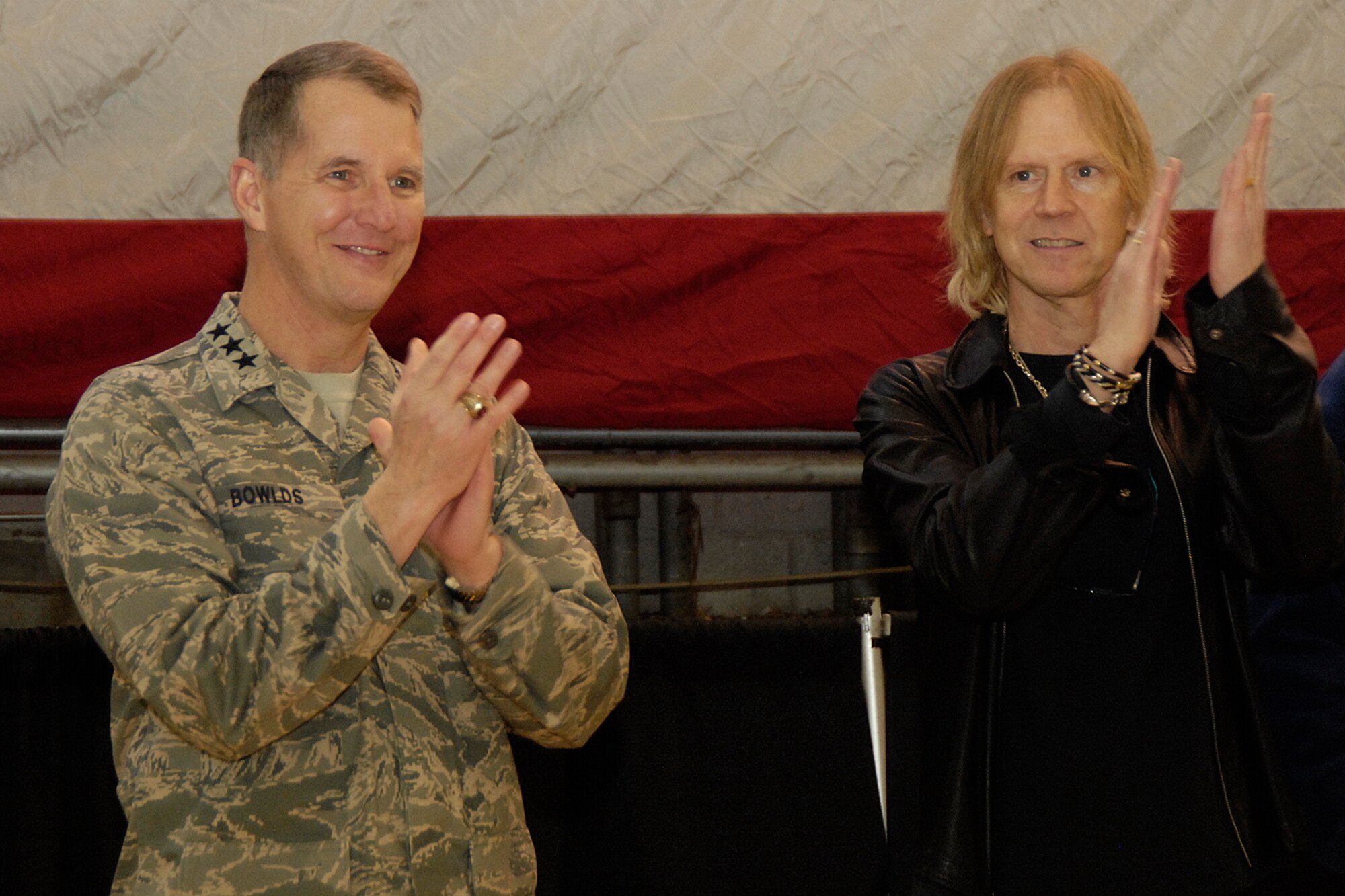 HANSCOM AIR FORCE BASE, Mass. – Lt. Gen. Ted Bowlds (left), Electronic Systems Center commander and Tom Hamilton (right), bassist for the rock group Aerosmith clap to the Air Force song at the conclusion of the Heroes’ Homecoming celebration on Dec. 12. The event officially welcomed home more than 45 Hanscom Airmen that have been deployed over the past six months and paid tribute to their families. (U.S. Air Force photo by Linda LaBonte Britt)