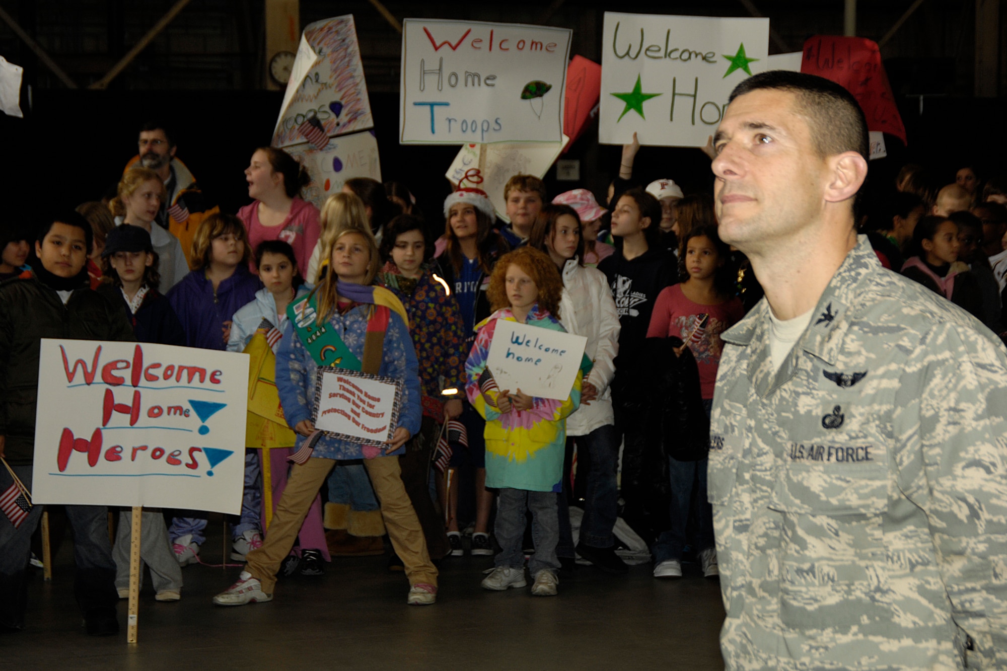 HANSCOM AIR FORCE BASE, Mass. – Col. Russell Fellers stands in formation while students from the Hanscom Middle School hold signs to welcome the Colonel and more than 45 Airmen home from deployments during the Heroes’ Homecoming celebration that took place Dec. 12 in the Aero Club hangar. The celebration included special appearances by Tom Hamilton of Aerosmith and Steve Grogan, former New England Patriots quarterback. (U.S. Air Force Photo by Linda LaBonte Britt)
