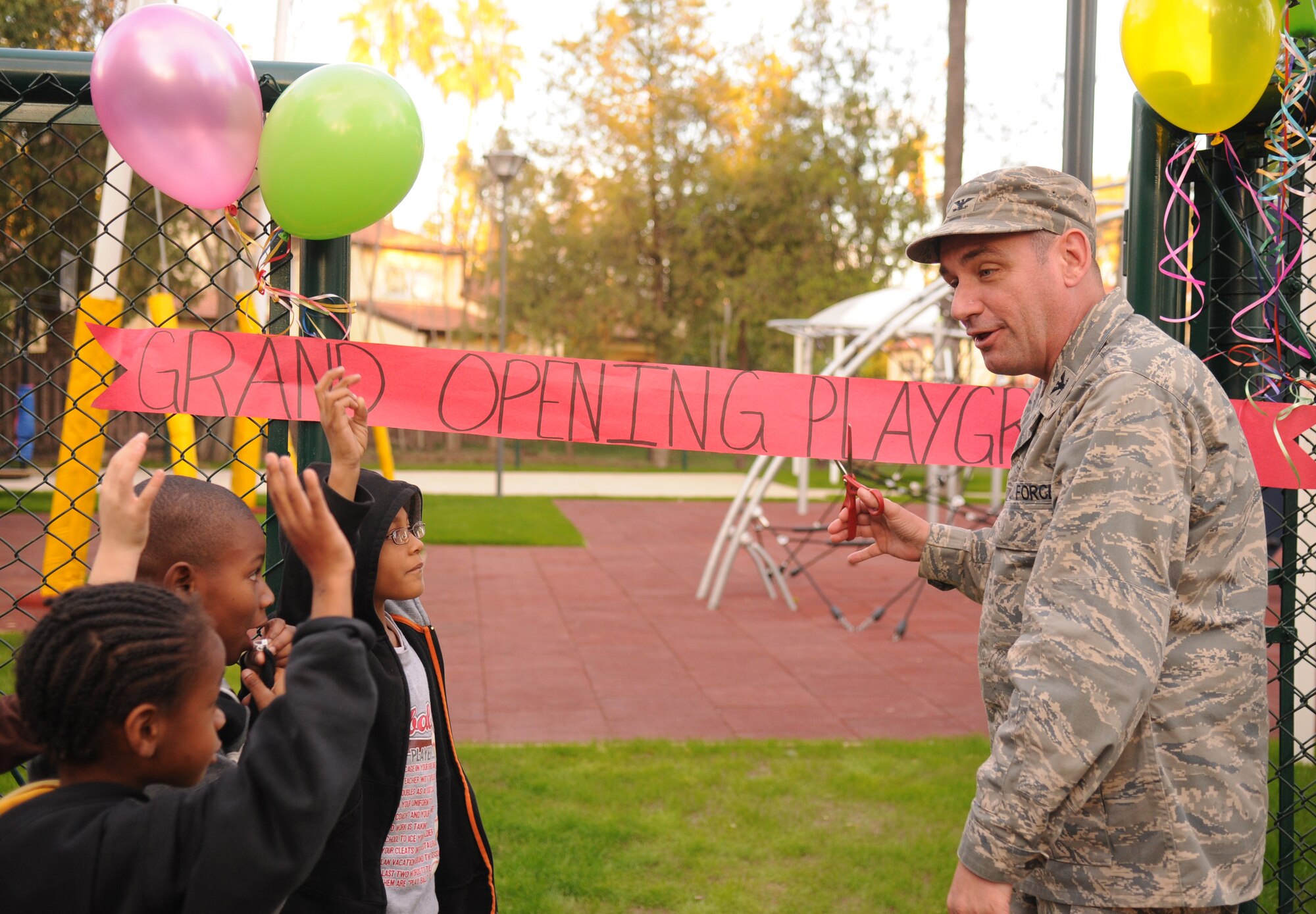 Col Andrew Pears, 39th Mission Support Group commander, clips the banner for the grand opening of the youth centers’ new playground Dec. 12, as children from the Youth Center wait excitedly.   (Air Force photo by Airman 1st class Amber Russell)