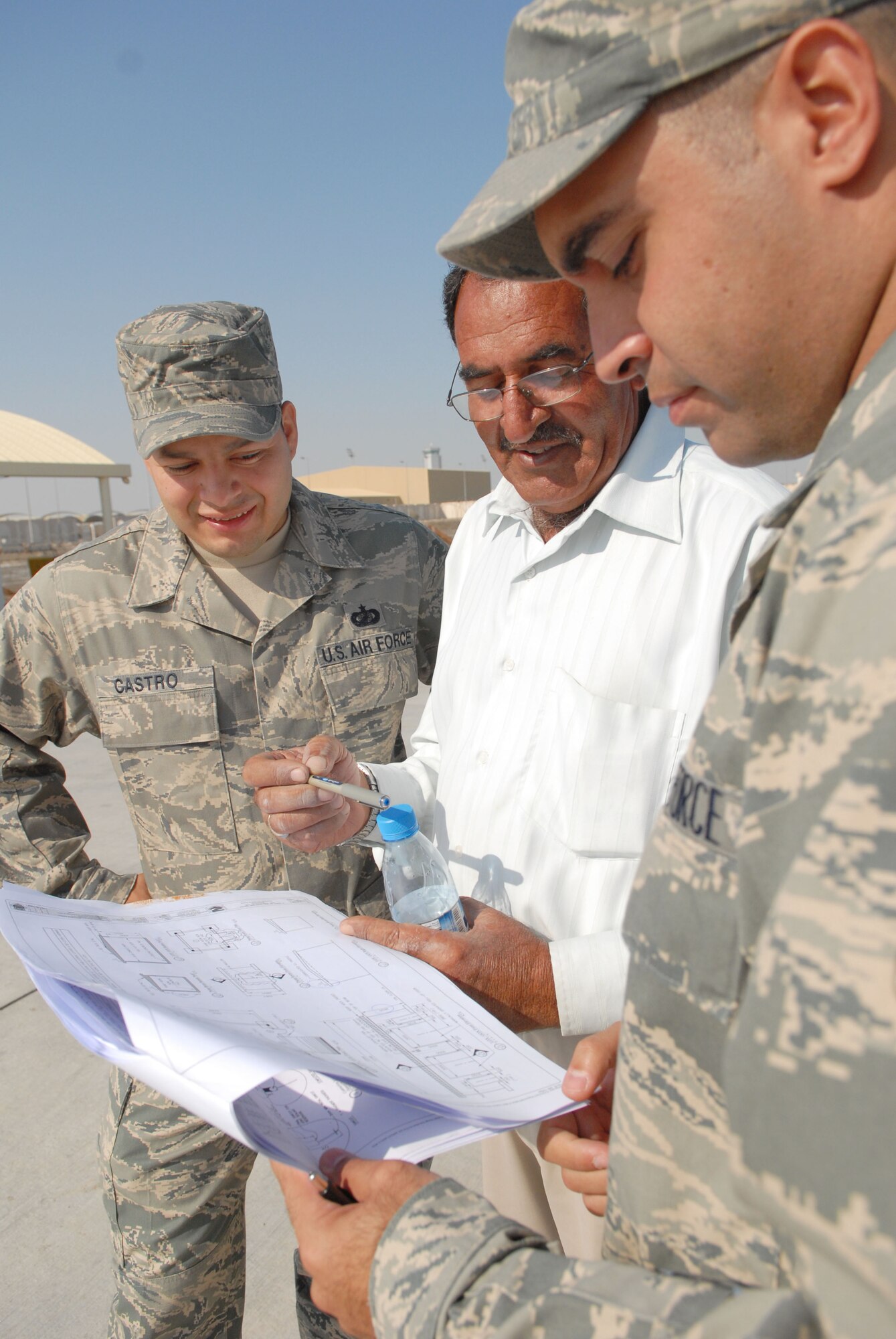 SOUTHWEST ASIA -- Staff Sgts. Arturo Castro (left) and Jamie Lugo (right) discuss plans with a contractor while third-country nationals begin the initial stages of construction on a liquid- and gas-oxygen storage facility here Dec. 14. Sergeant Castro is a contracting technician from the 380th Expeditionary Contracting Squadron and Sergeant Lugo is from the 380th Expeditionary Civil Engineer Squadron. (US Air Force photo by Tech. Sgt. Denise Johnson) (released)