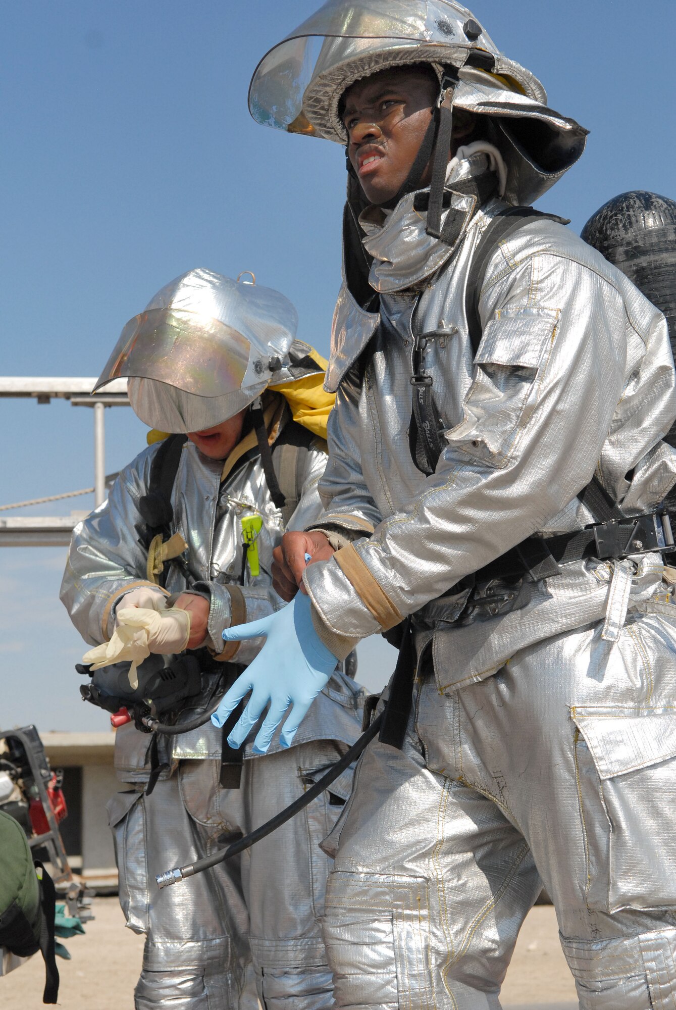 SOUTHWEST ASIA -- Airmen 1st Class Courtland Dickerson and Ryan Britz, both fire protection journeymen with the 380th Expeditionary Civil Engineer Fire and Emergency Services Flight, don protective gloves as they head toward a simulated mass-casualty scene after a simulated terrorist attack here Dec. 12. The deployed Airmen are all taking part in an exercise which tests and evaluates the 380th Air Expeditionary Wing's response to real-world scenarios. (US Air Force photo by Tech. Sgt. Denise Johnson) (released)