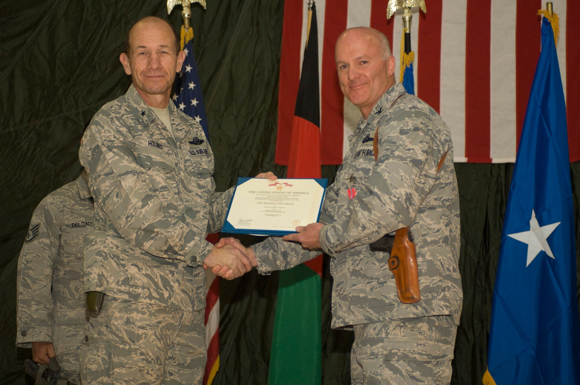 Brig. Gen. Mike Holmes, 455th Air Expeditionary Wing commander, presents Col. Luther Turner, 451st Air Expeditionary Group commander, with the Bronze Star Medal during a change of command ceremony Dec. 13 at a base in Southern Afghanistan. After serving as 451st AEG commander for nearly a year, Colonel Turner relinquished command to Col. Theodore Osowski. (U.S. Air Force photo by Staff Sgt. Rachel Martinez) (Released)