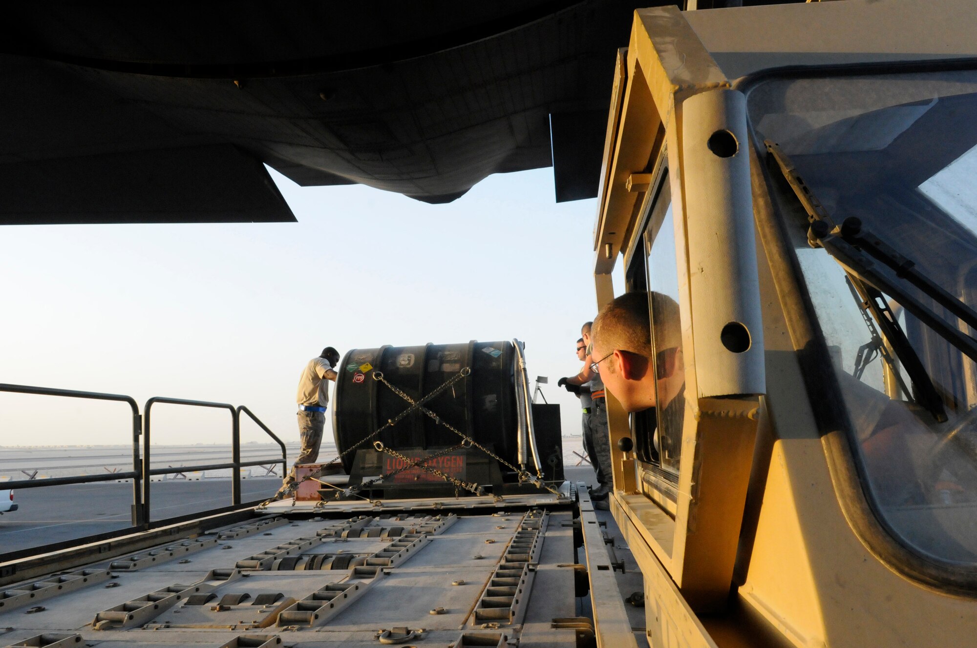 Airman 1st Class Gabriel Griggs, an air transportation journeyman assigned to the 8th Expeditionary Air Mobility Squadron, watches progress as he uses controls of a K-loader to move a pallet with a liquid oxygen container into a C-130 Hercules, Dec. 13, at an undisclosed air base in Southwest Asia.  The C-130 primarily performs the tactical portion of the airlift mission. The aircraft is capable of operating from rough, dirt strips and is the prime transport for air dropping troops and equipment into hostile areas in the Central Command area of responsibility.  Airman Griggs, a native of Tucson, Ariz., is deployed from Little Rock Air Force Base, Ark., in support of Operations Iraqi and Enduring Freedom and Joint Task Force-Horn of Africa.  (U.S. Air Force photo by Tech. Sgt. Michael Boquette/Released)
