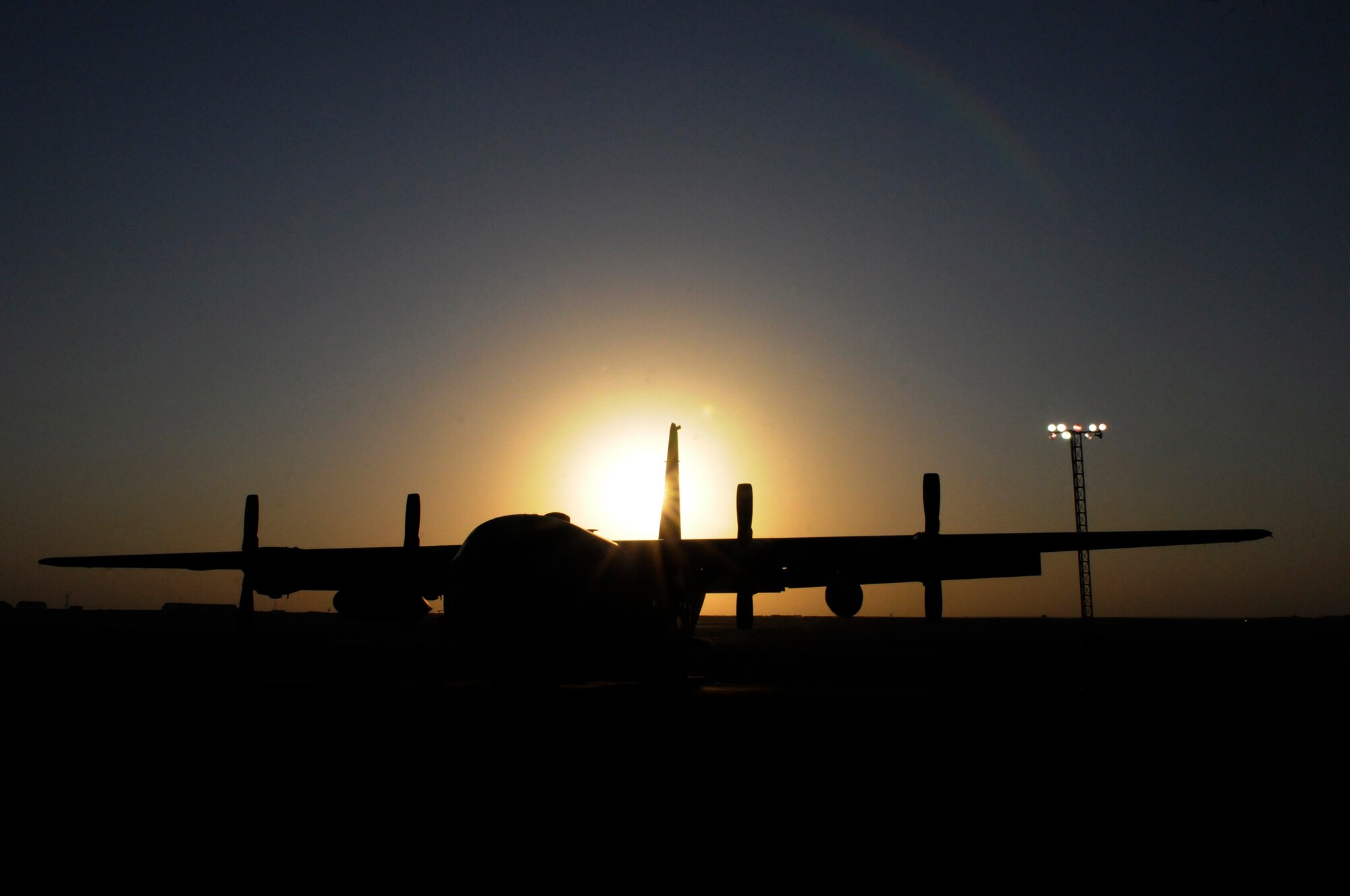 A C-130 Hercules is silhouetted against the setting sun, Dec. 13, at an undisclosed air base in Southwest Asia.  The C-130 primarily performs the tactical portion of the airlift mission. The aircraft is capable of operating from rough, dirt strips and is the prime transport for air dropping troops and equipment into hostile areas in the Central Command area of responsibility.  (U.S. Air Force photo by Tech. Sgt. Michael Boquette/Released)