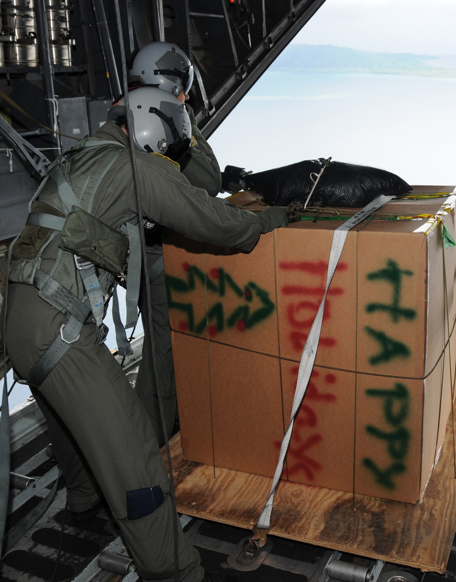ANDERSEN AIR FORCE BASE, Guam - Capt. John Fuccillo and Master Sgt. Sigrid Carrero-Perez, both from the 36th Airlift Squadron, Yokota Air Base, Japan, prepare to drop a package over a remote island near Chuuk Dec. 14. Over 600 pounds of donated goods will be dropped over the remote islands during Operation Christmas Drop. (U.S. Air Force photo by Staff Sgt Jamie Lessard)