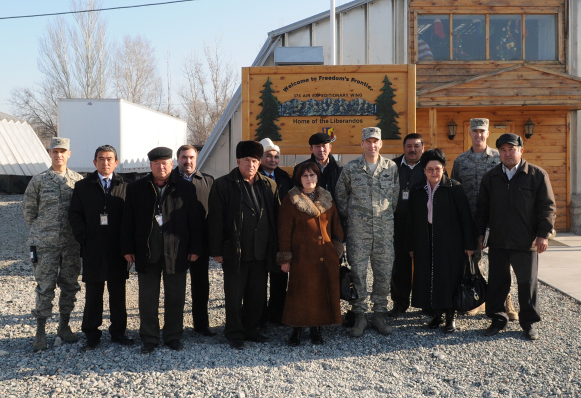 Nearly a dozen mayors and their deputies from six local Kyrgyz villages pose for a group picture with (left to right) Col. David MacMillan, 376th Air Expeditionary Wing vice commander, Col. Christopher Bence, 376th AEW commander and Chief Master Sgt. Kevin Soltis, 376th AEW command chief, before kicking off a tour of Manas and lunch with wing leadership, Dec. 10. The visit provided an opportunity to strengthen friendships and discuss issues affecting the local villages that the base can assist with. (Air Force photo / Senior Airman Ruth Holcomb) 	