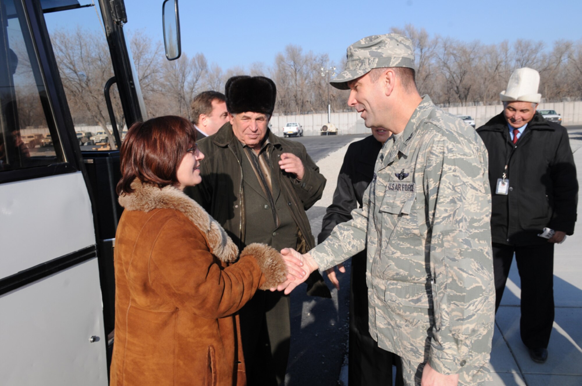 Col. Christopher Bence, 376th Air Expeditionary Wing commander, greets Magiyat Abakirova, chief accountant for Jany Pakhta village, as she and mayors and deputy mayors from local Kyrgyz villages arrive at Manas for a tour of the base and lunch with wing leadership, Dec. 10. The visit provided an opportunity to strengthen friendships and discuss issues affecting the local villages that the base can assist with. (Air Force photo / Senior Airman Ruth Holcomb) 	
